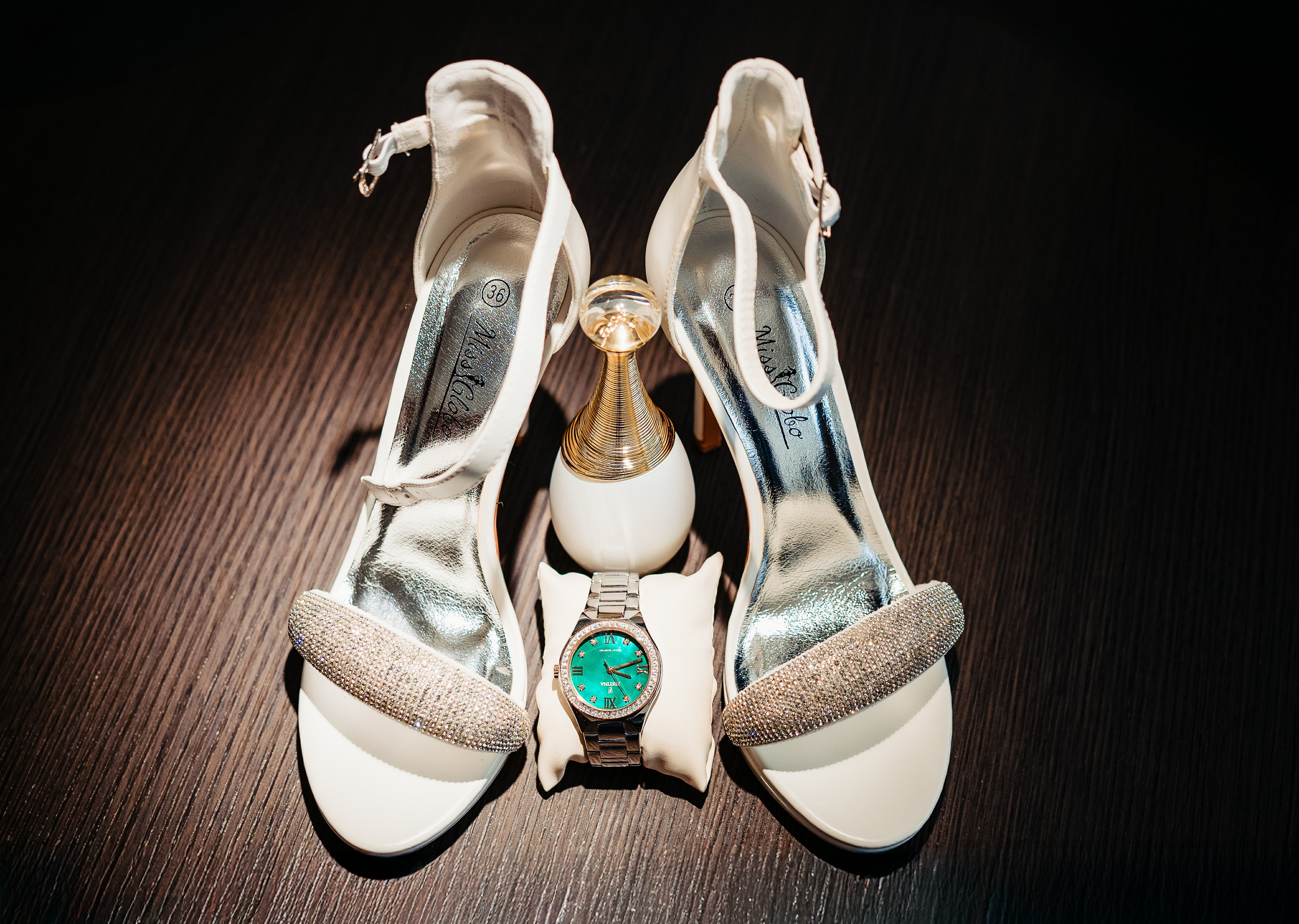 Detalii cu verighetele, parfumul și invitațiile pe o masă elegantă