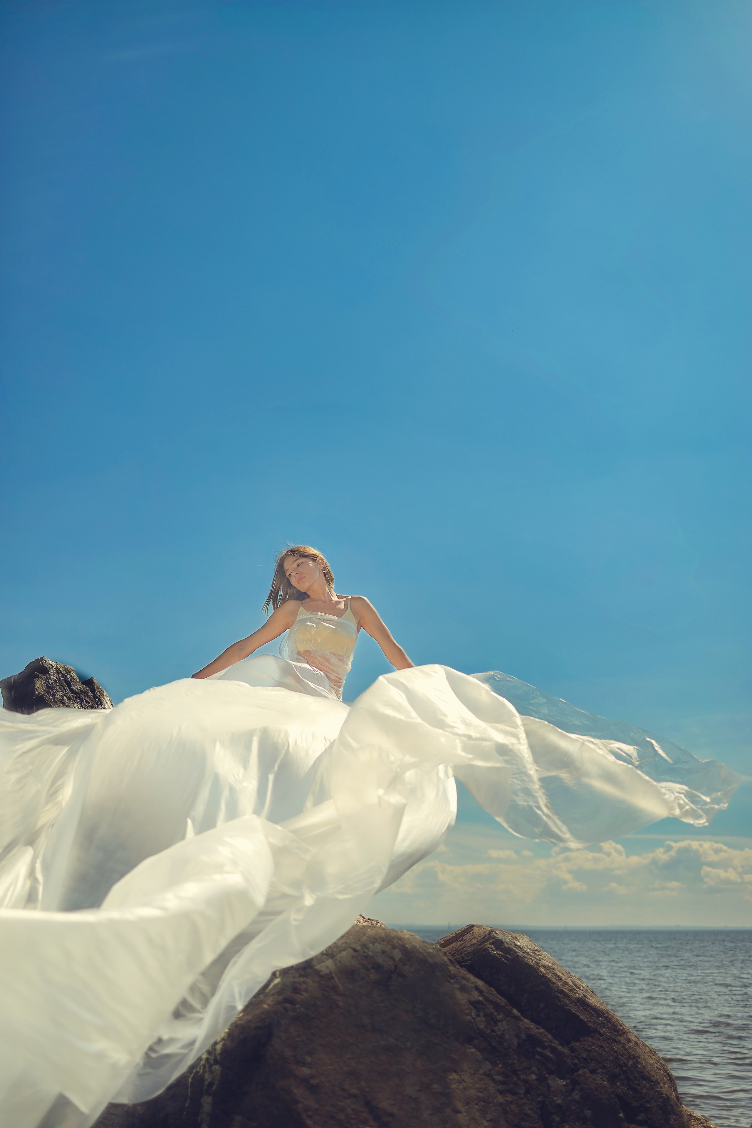 Уличная фотосесия девушка в парящем платье на камне, на берегу