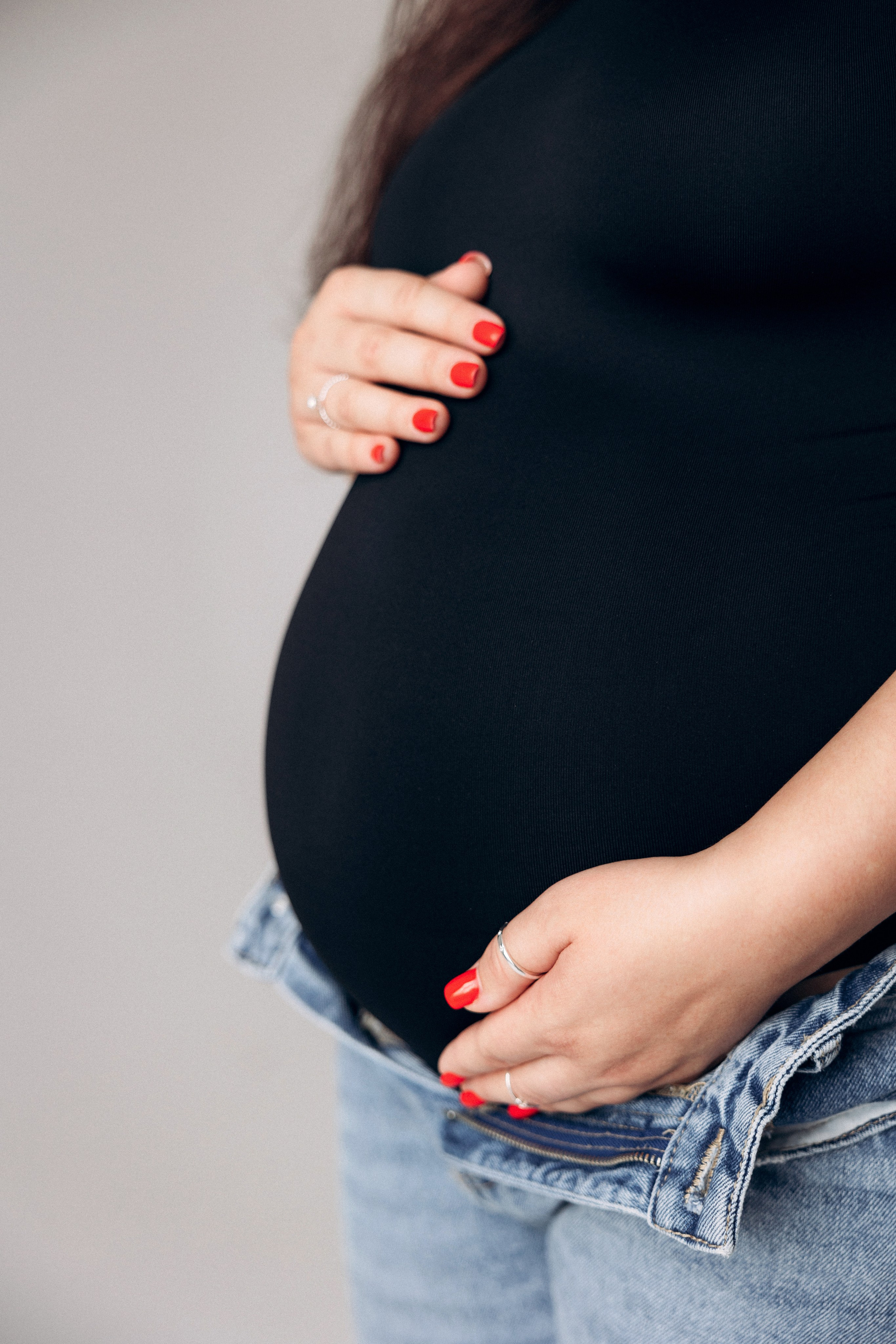 Detal miłości – dłonie na ciążowym brzuchu, symbol czekania i czułości.