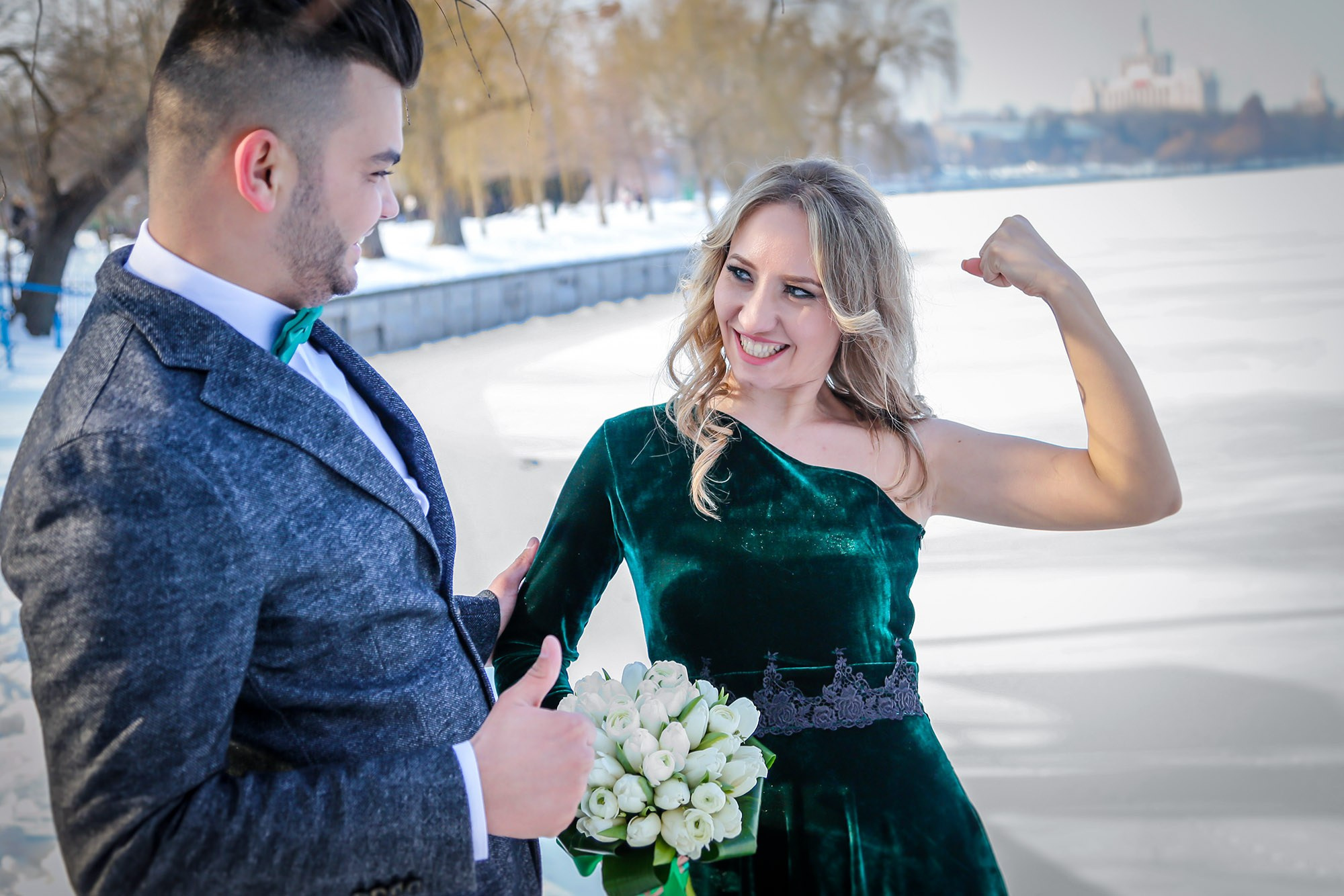 Funny and playful pose during the winter wedding shoot, with the bride jokingly showing off her muscles.