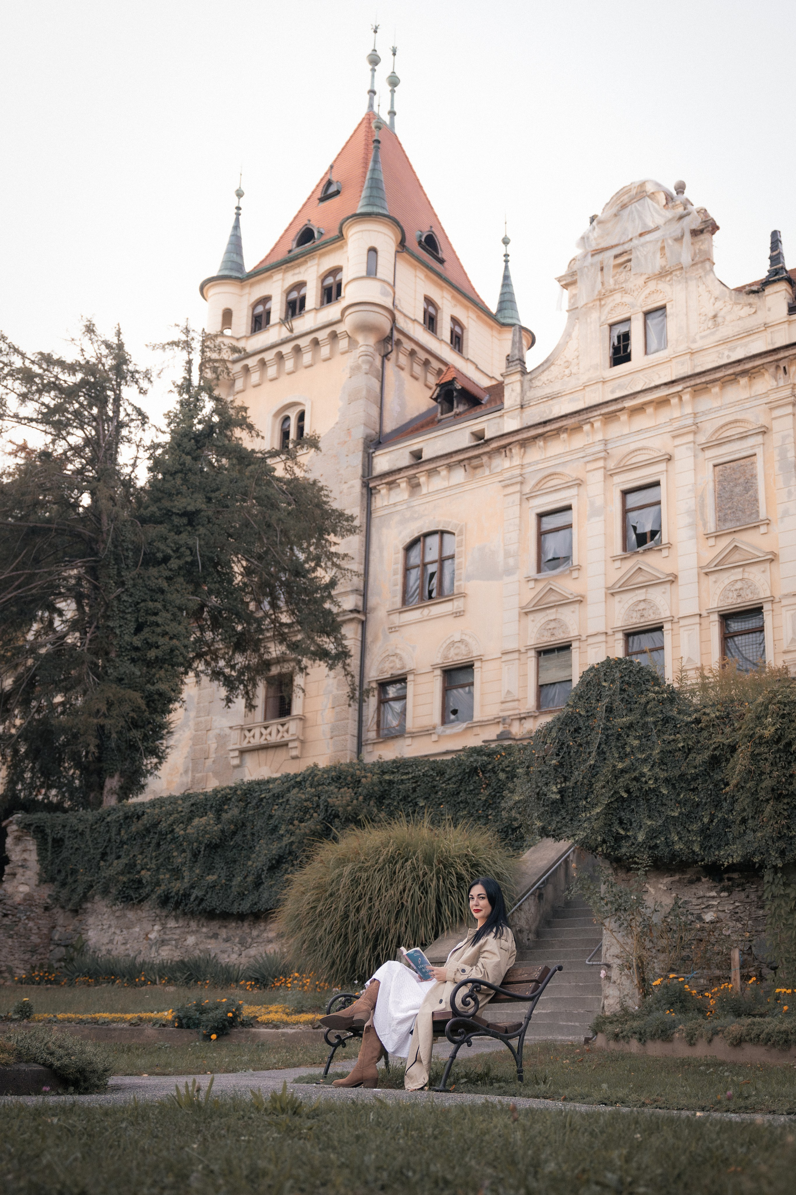 Ženska v klobuku pred dvorcem Viltuš. Fotografija prikazuje prefinjeno gradacijo svetlobe s prehodom iz mehkih osvetljenih delov v globoke mat sence, kar poudari teksturo kamna.9
