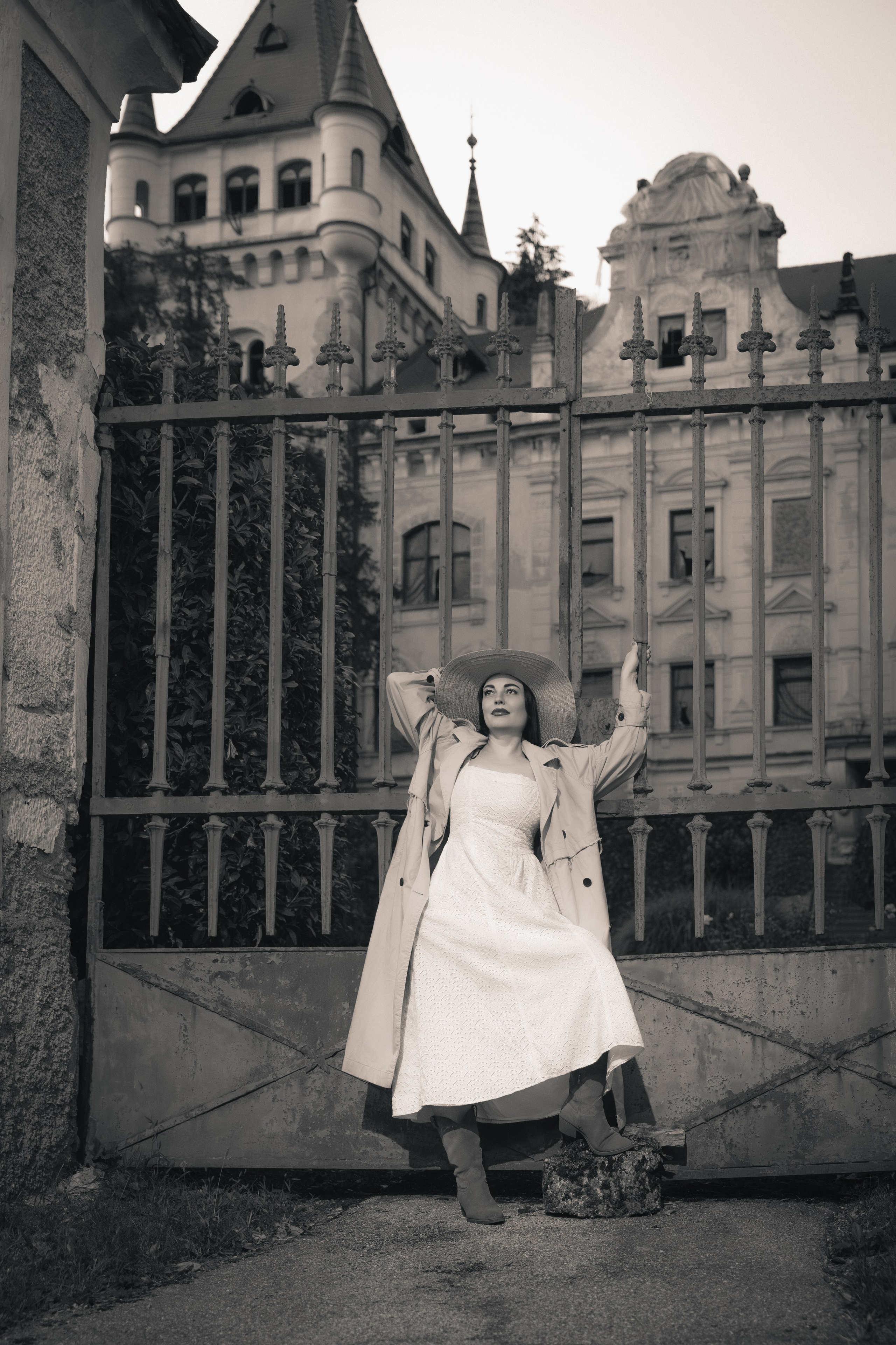 Ženska v klobuku pred dvorcem Viltuš. Fotografija prikazuje prefinjeno gradacijo svetlobe s prehodom iz mehkih osvetljenih delov v globoke mat sence, kar poudari teksturo kamna.1988
