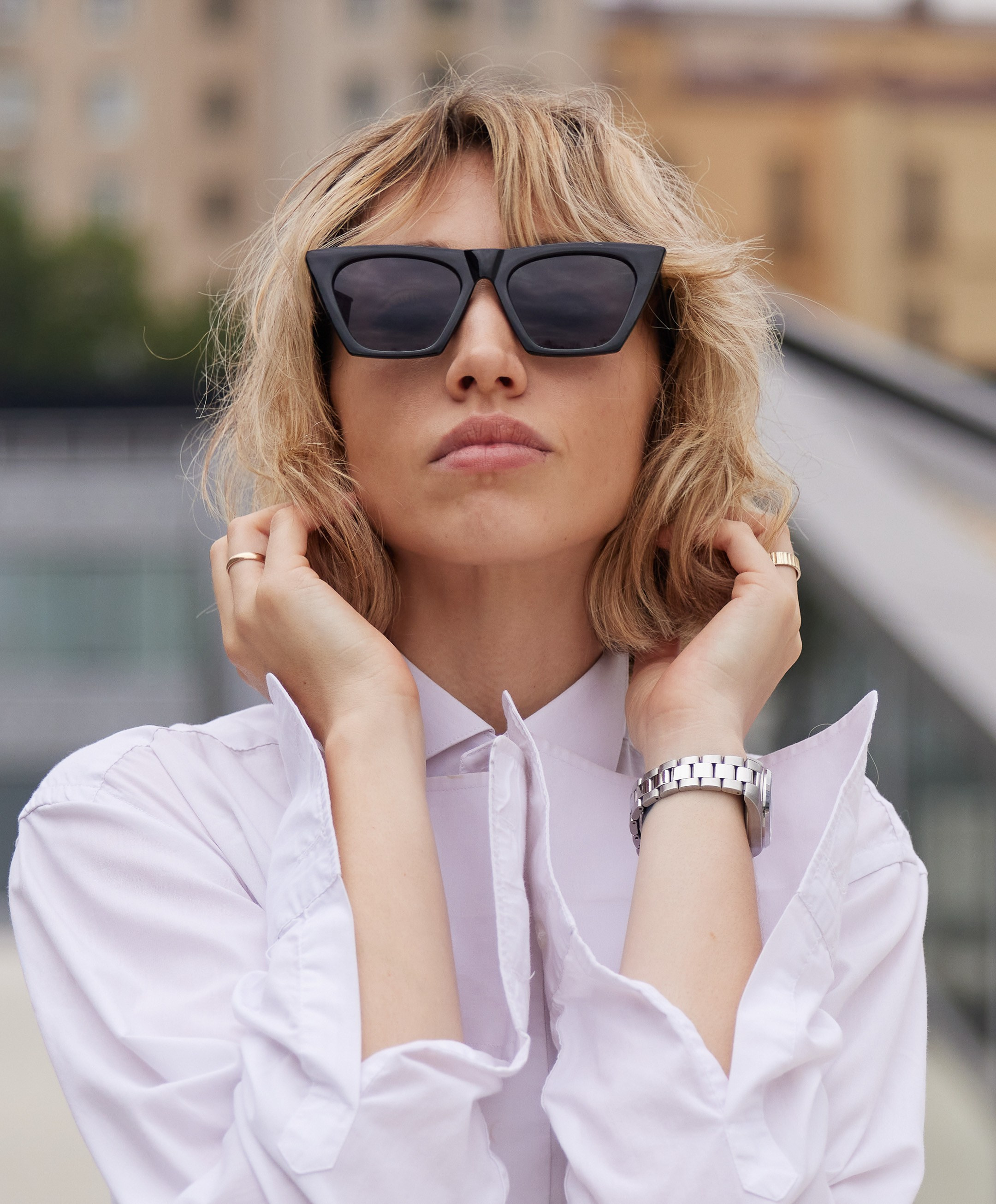 Location portrait of a young woman in sunglasses against the backdrop of a building - photographer Andrey Dunin