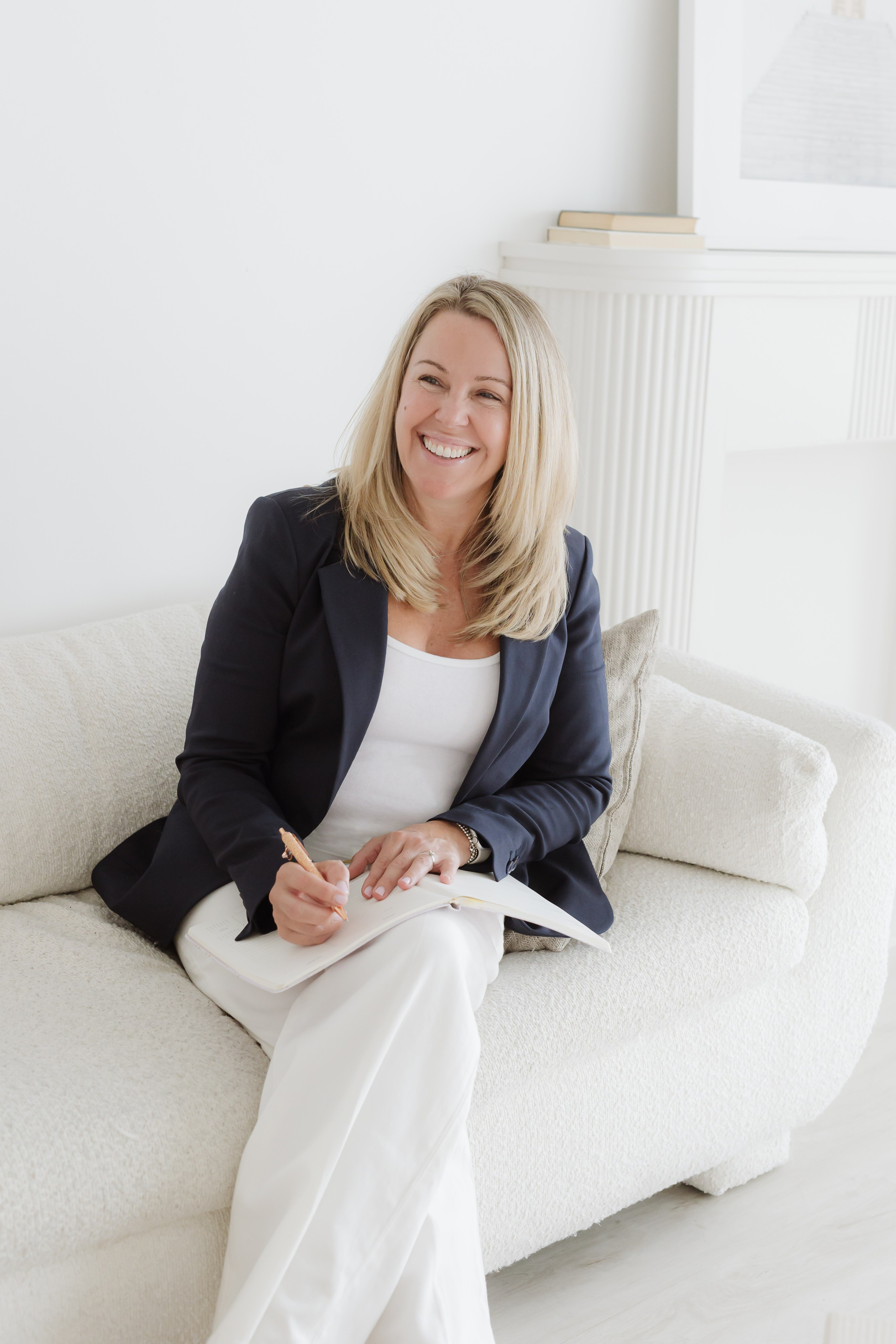 headshot of a woman in white and black sitting on a white couch in office 