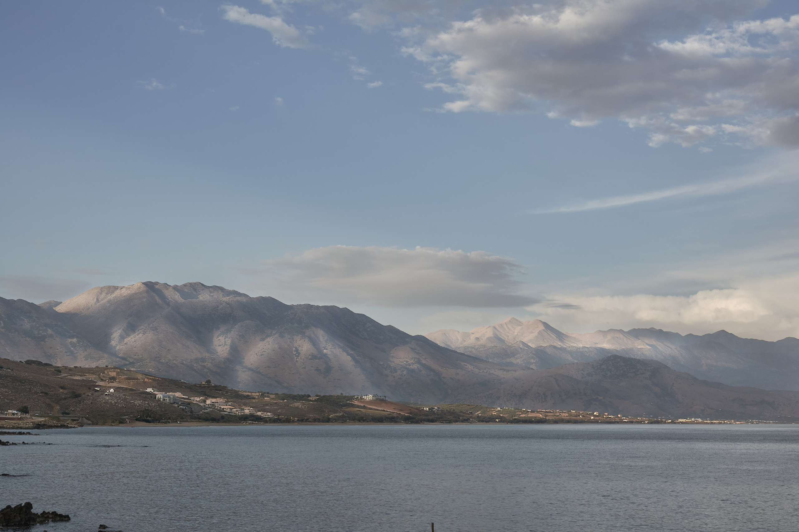 Calm sea bay beneath snow-capped mountain range