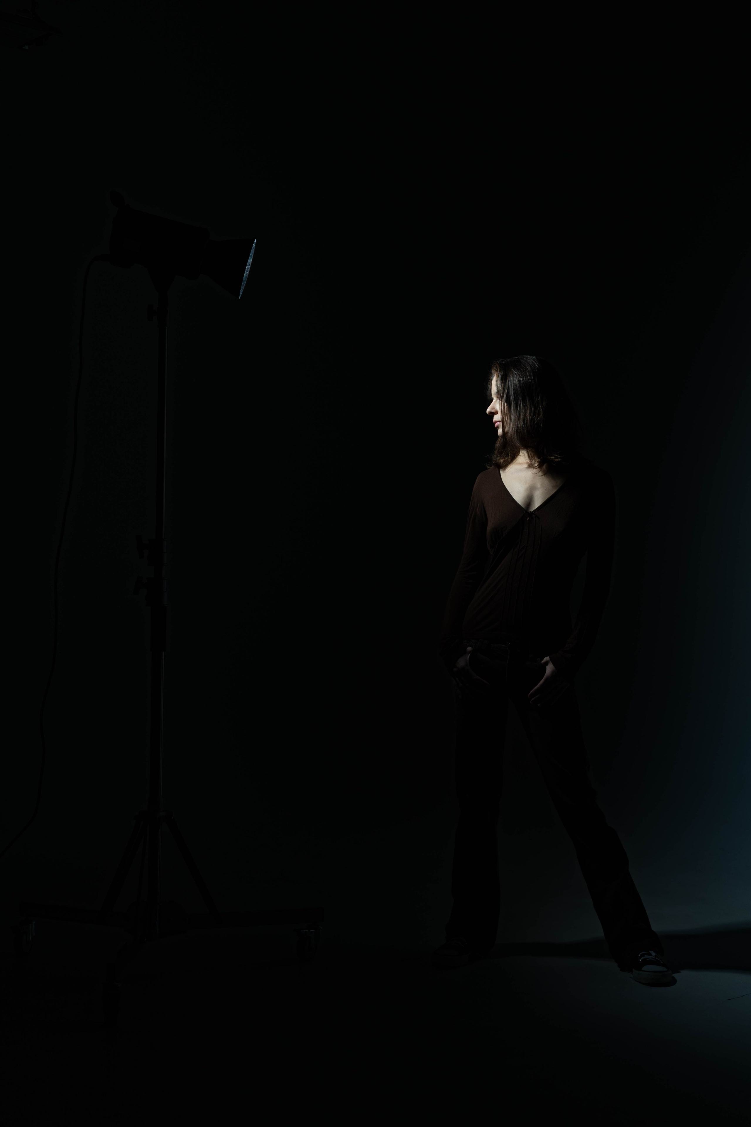 Художественная фотография девушки на тёмном фоне, акцент на лице и свете