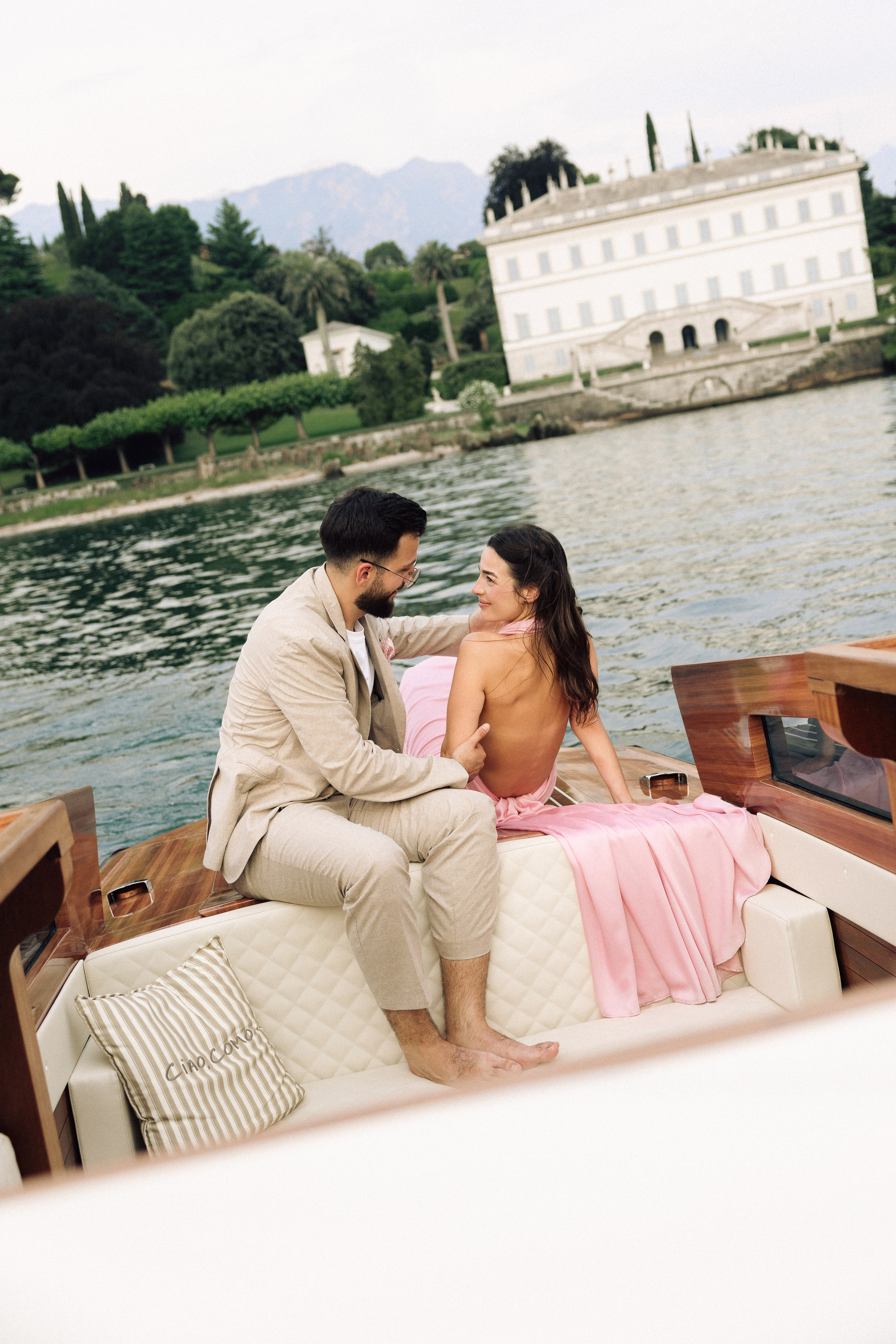Couple cruising on Lake Como with the gardens and historic architecture of Villa Melzi in view