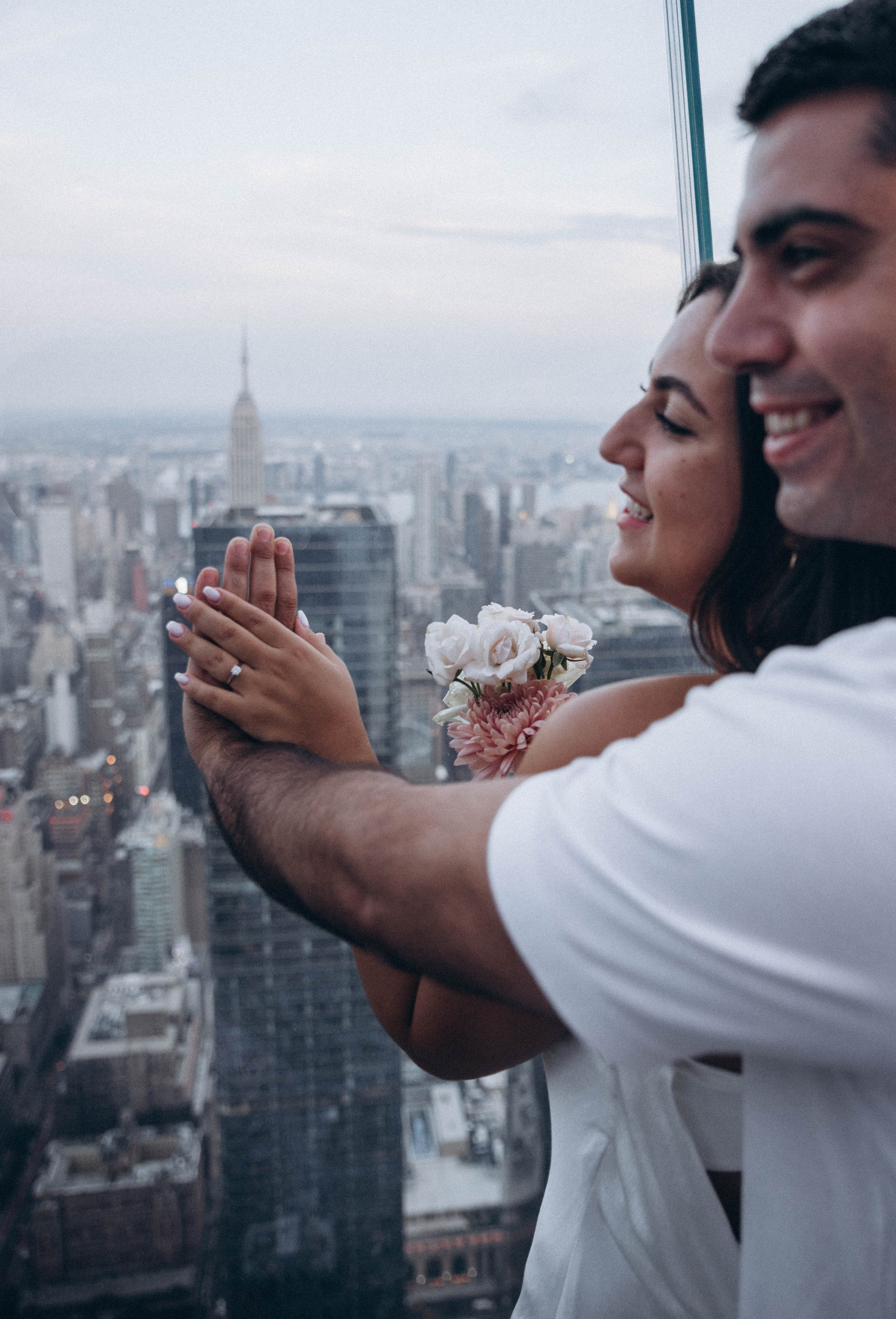 Man kneeling with ring box near Gapstow Bridge.