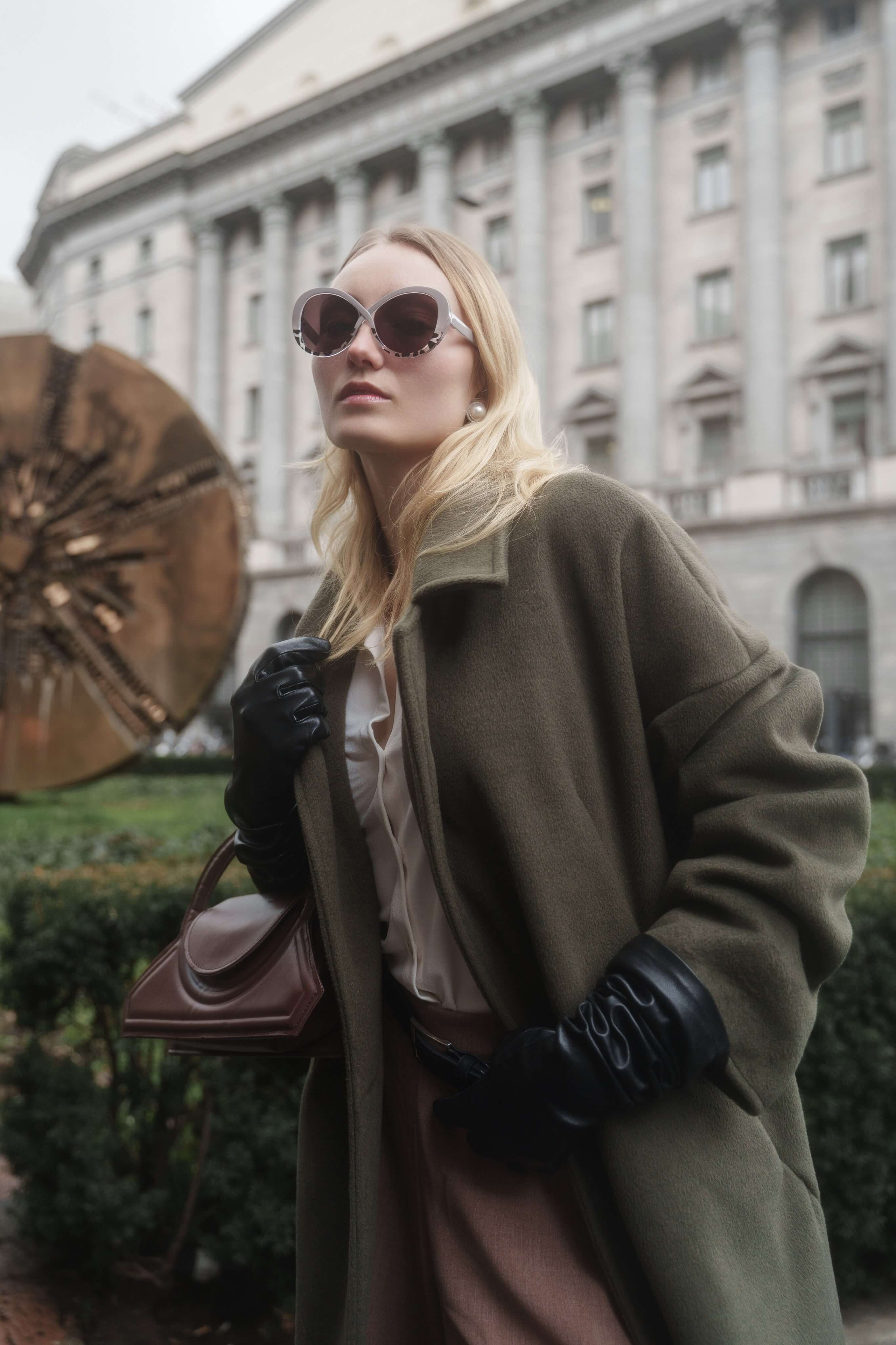 Female model wearing oversized sunglasses in front of iconic Milan architecture – editorial eyewear campaign photography