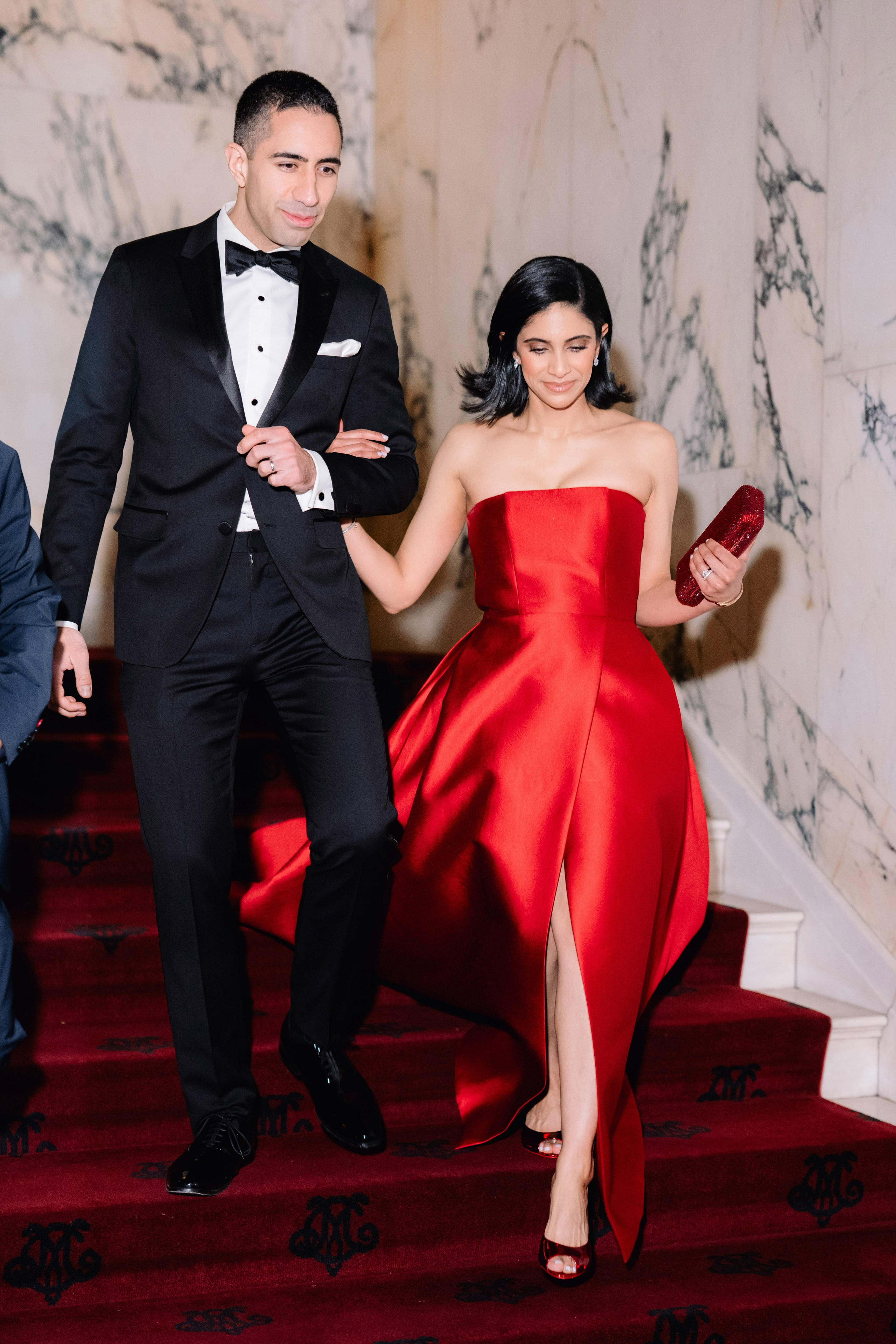 a man and woman in formal attire walking up a red carpet