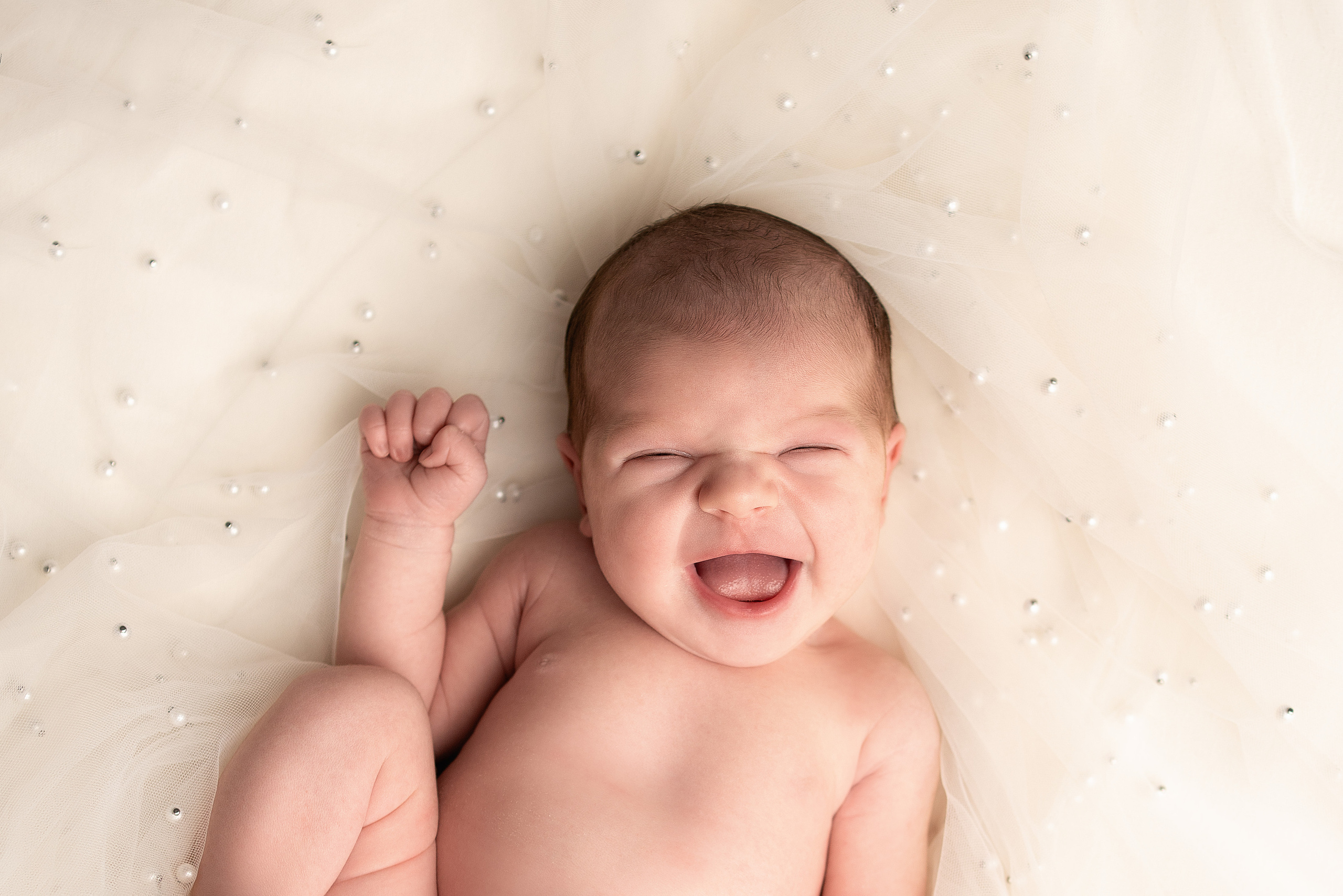 Verträumte gelächelte Neugeborene im weichen Licht