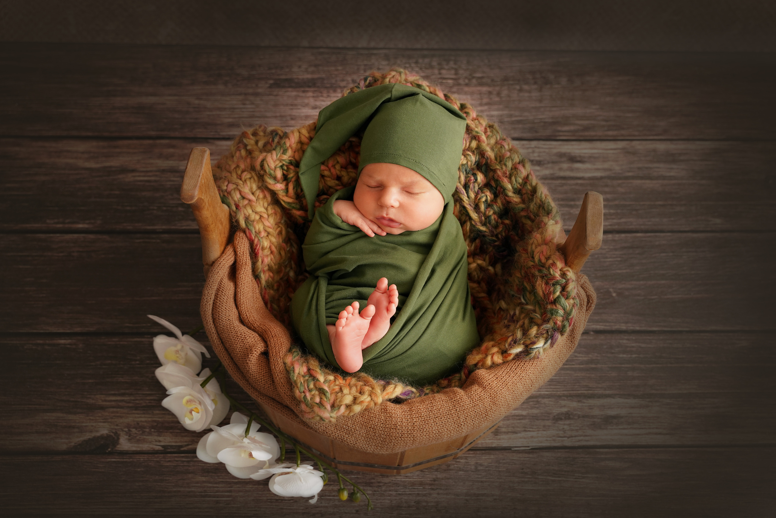 Ein Kind wird zusammengerollt in einem Holzbecken fotografiert