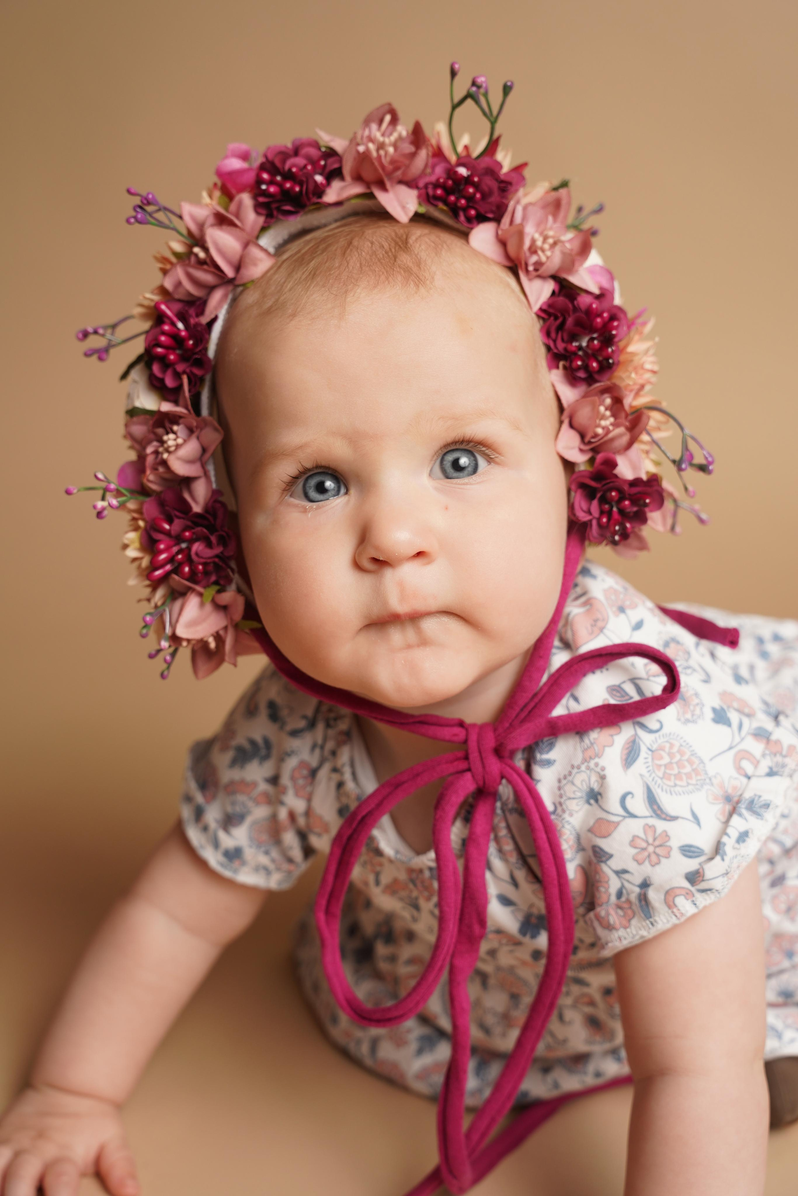 Kleiner Engel mit Blumenkrone schaut in die Kamera
