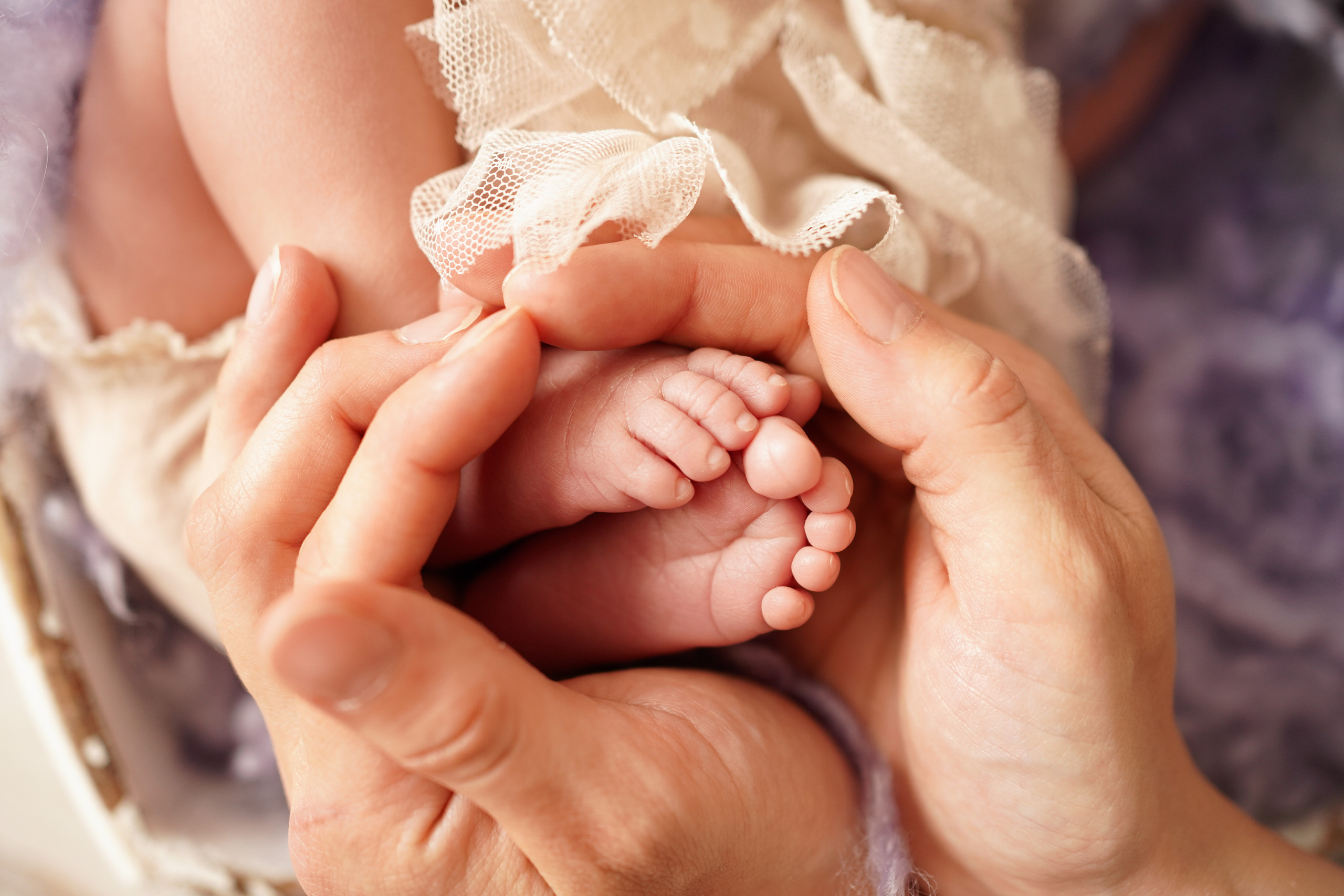 Die Hände der Eltern umfassen sorgfältig die Zehen ihres Sohnes