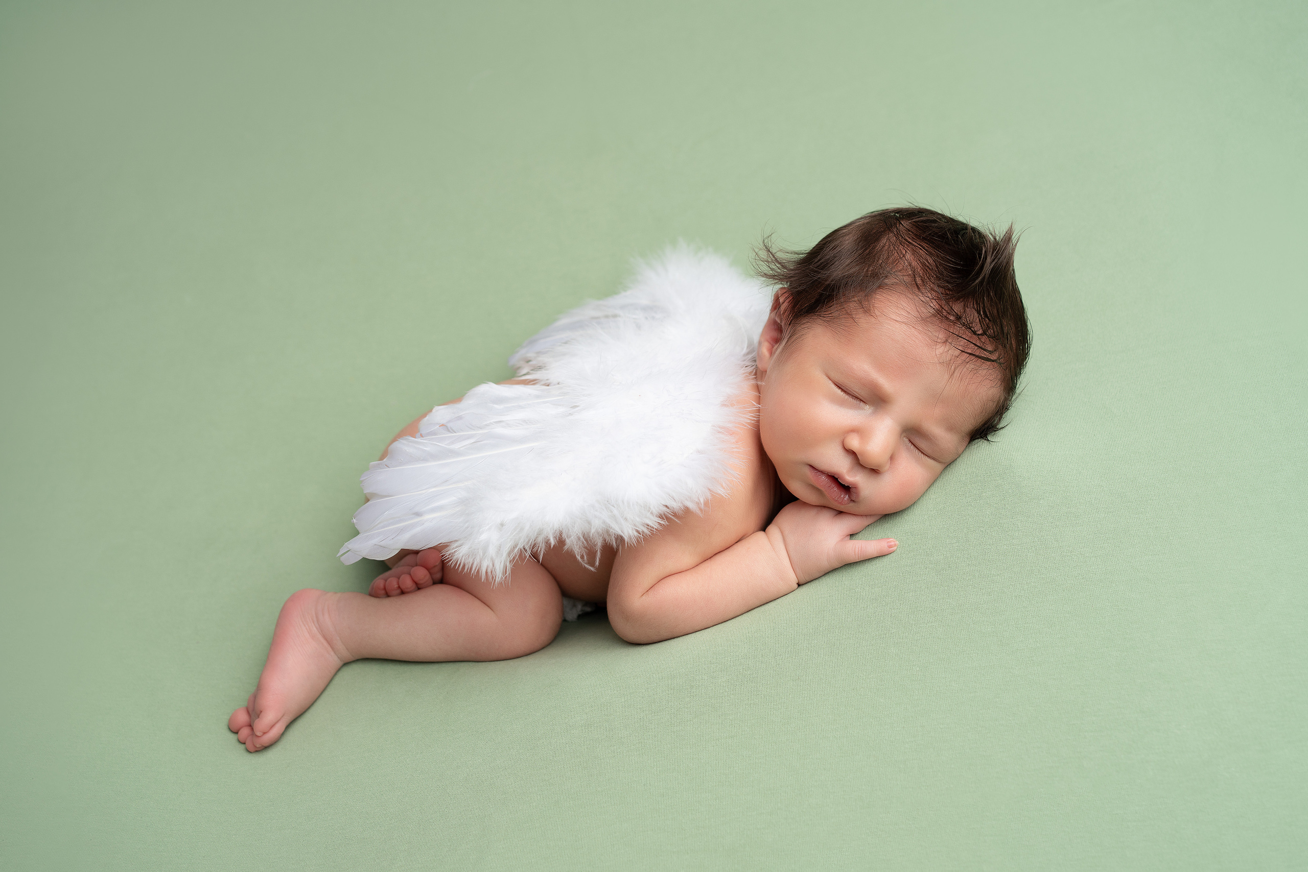 Grüne Akzente und Babyflügel für Neugeborenenfotos