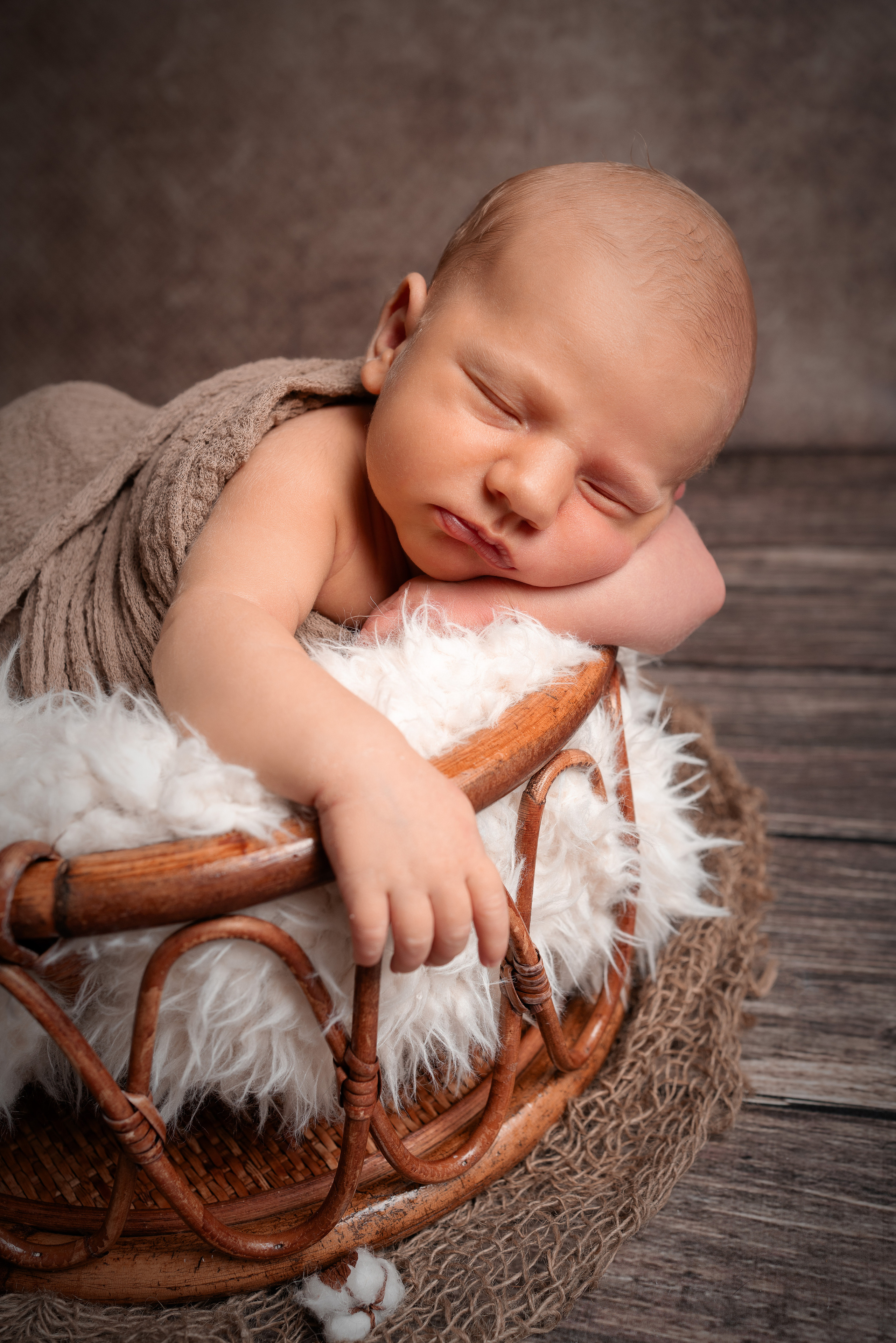 Baby in einer Eimer auf dem Bauch mit der Händen  unter dem Kinn
