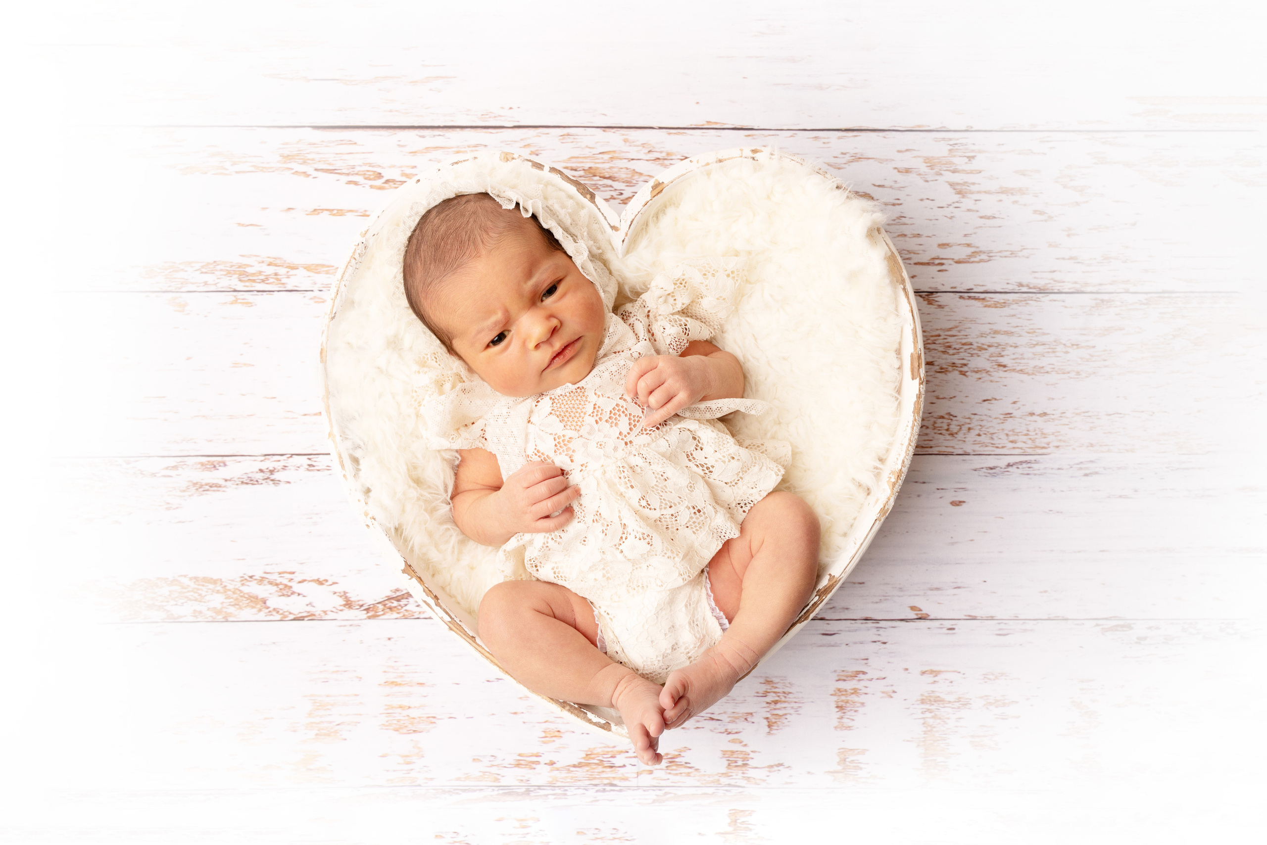 Baby fotografiert in einem dekorativen Herzen in zarten hellen Farben