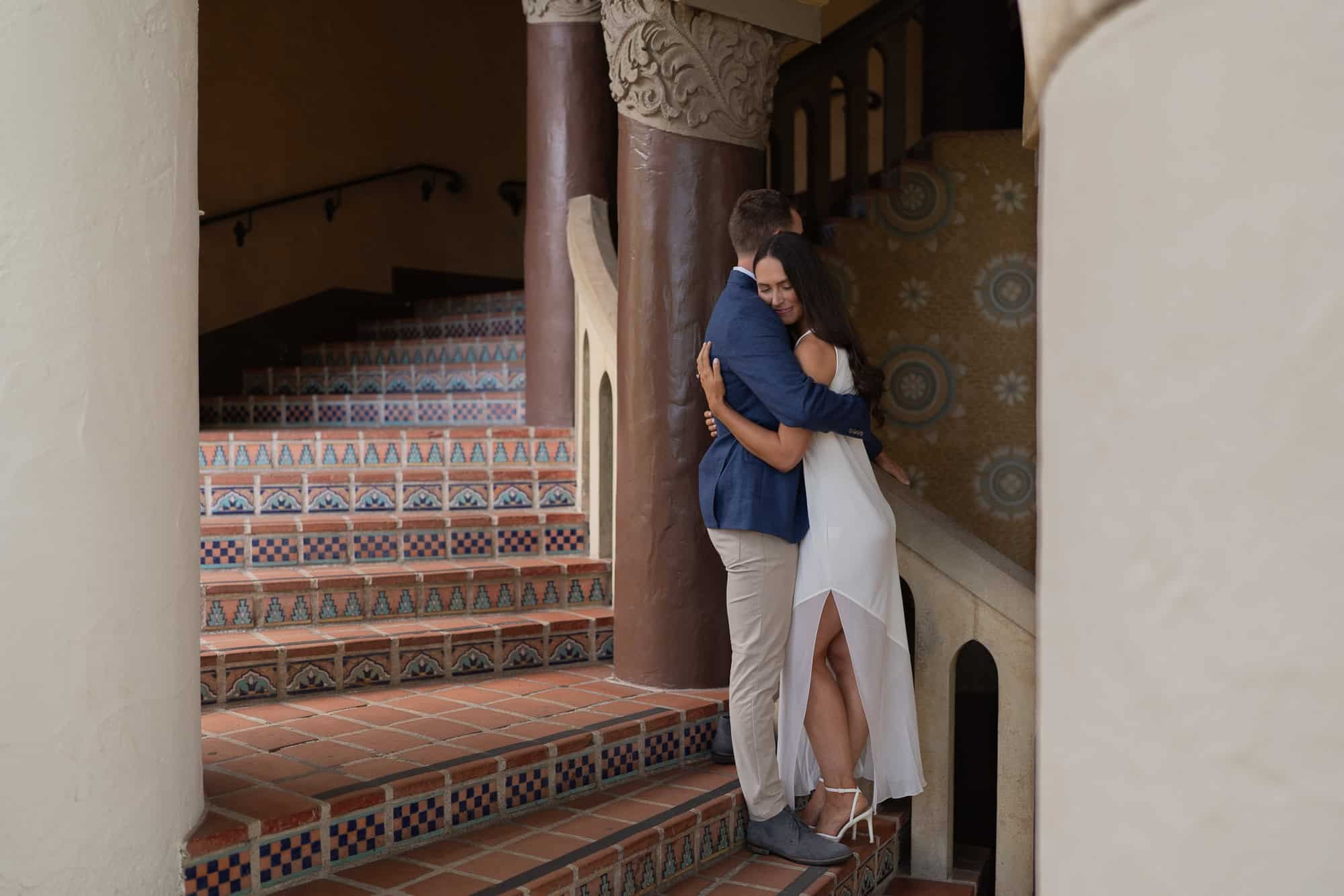 Couple hugging on tiled staircase inside Santa Barbara Courthouse 