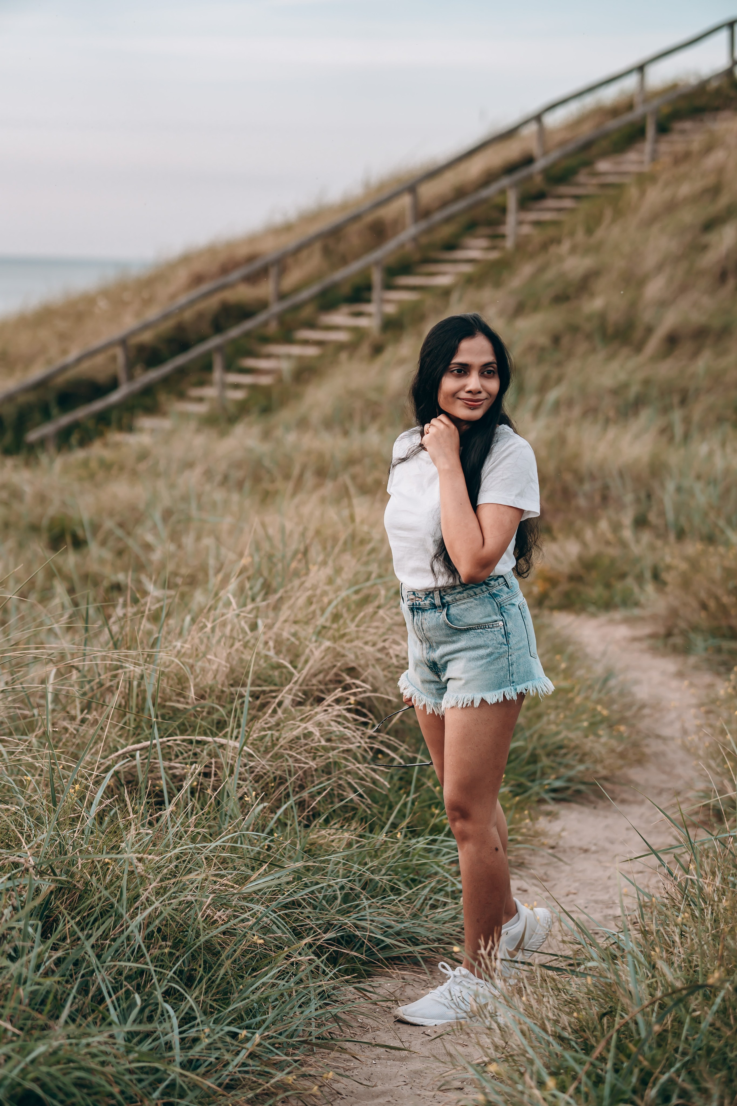 Woman walking along a narrow path close to the beach