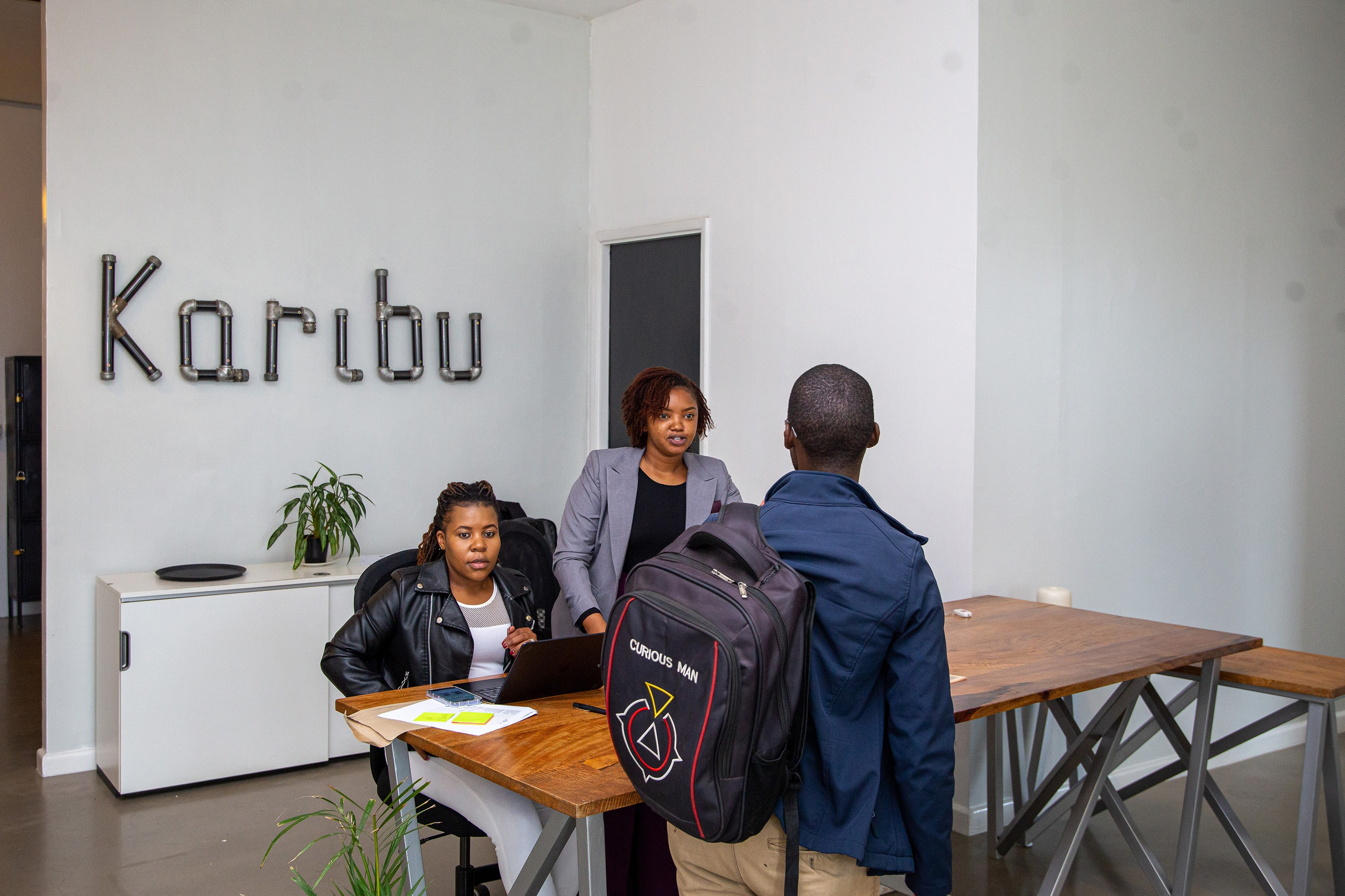 Attendee welcomed by two hostesses at a corporate event registration desk, in Nairobi.