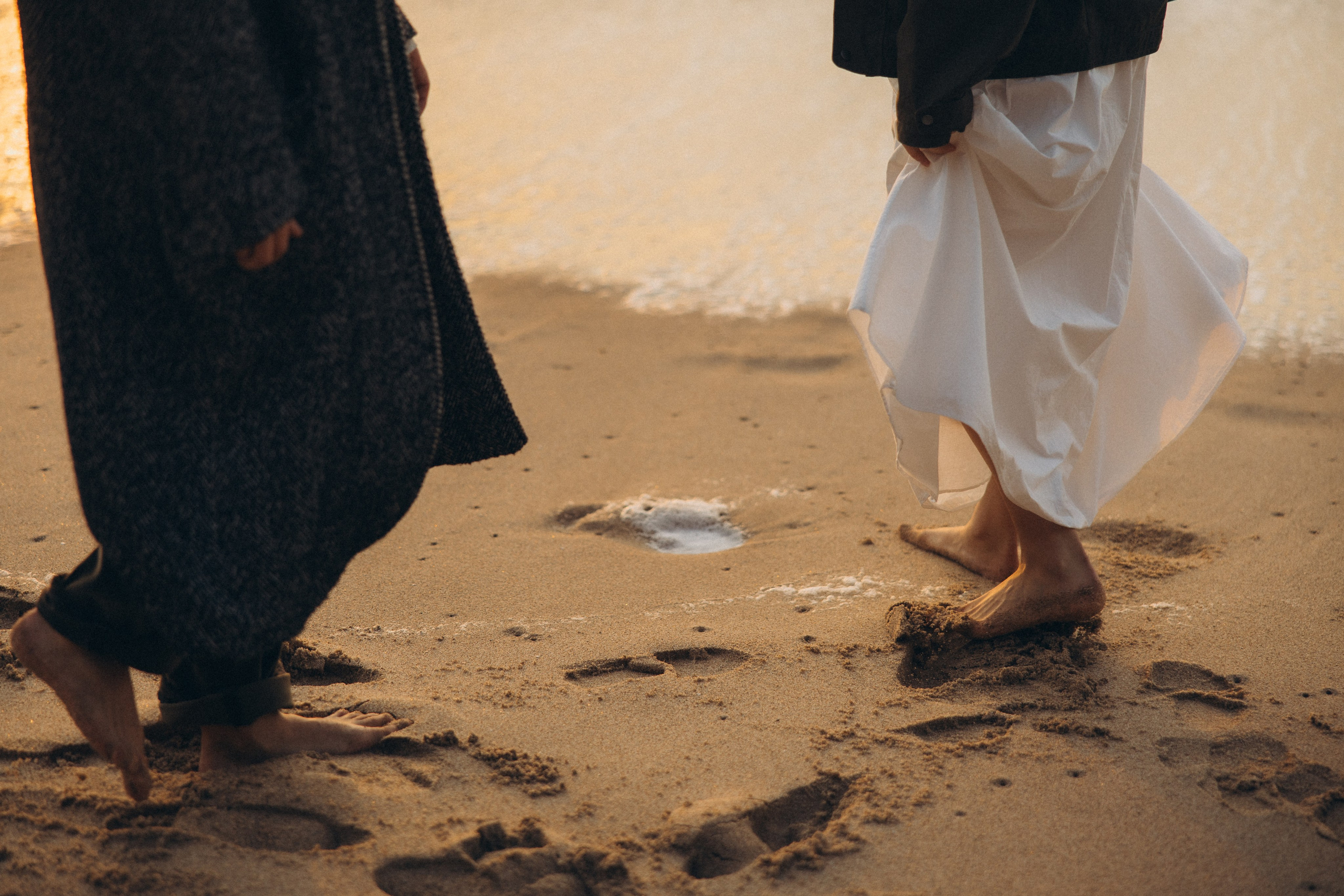 Couple holding hands and walking through a picturesque coastline in Portugal.