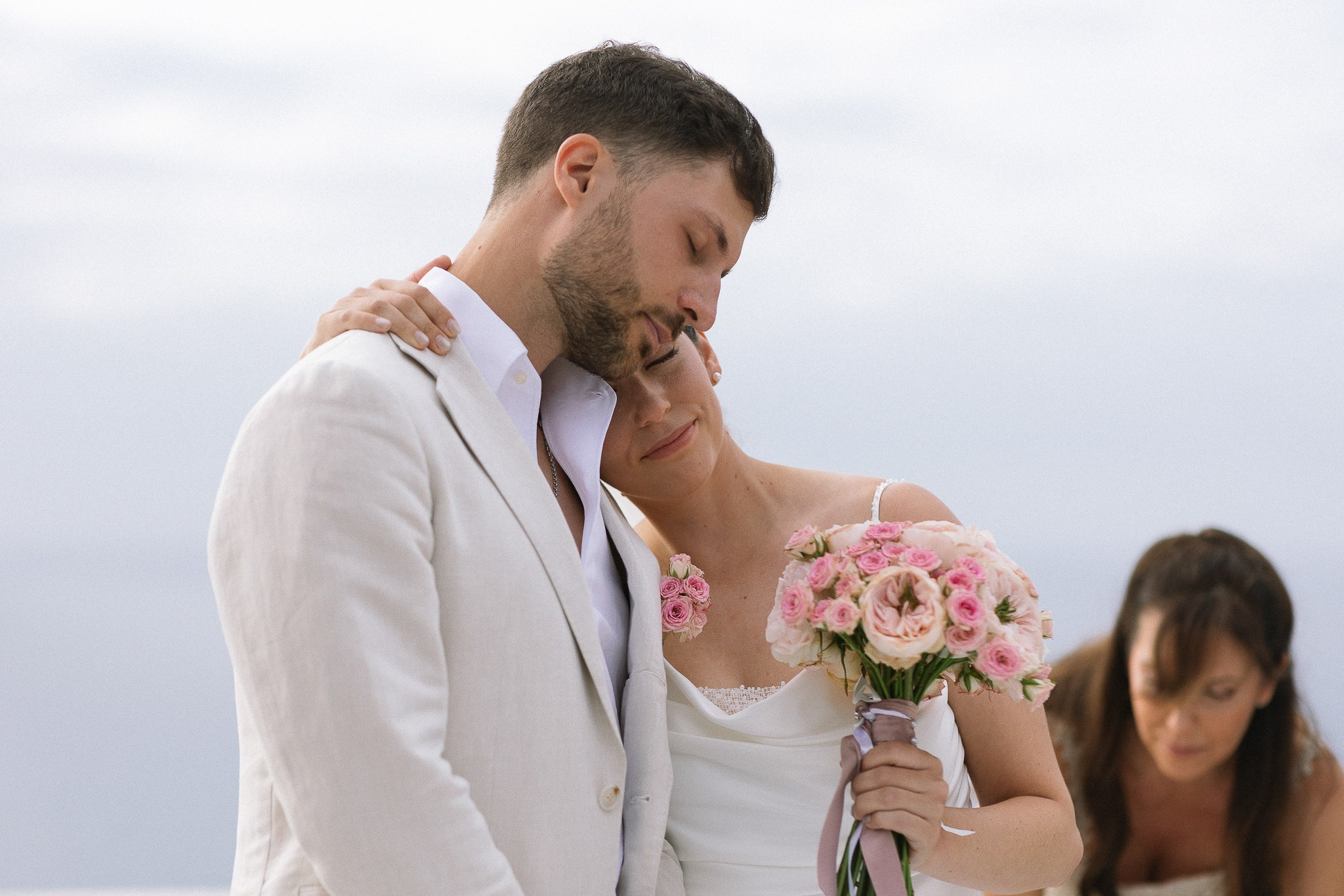 Bride resting head on groom's shoulder during ceremony