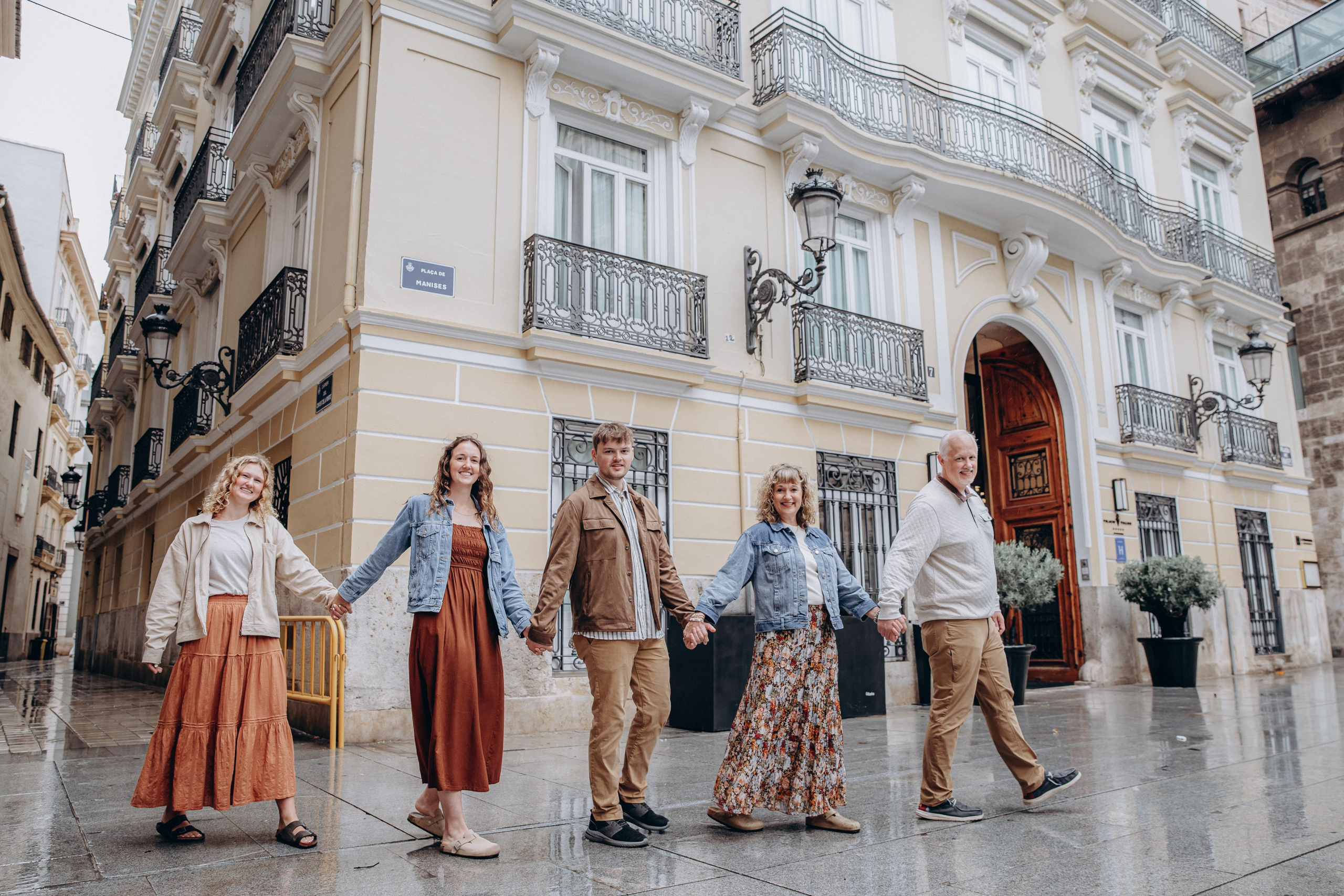 Familia caminando de la mano por las encantadoras calles históricas de Valencia, España, durante una sesión familiar espontánea. Imagen perfecta para quienes buscan fotografía relajada y natural en Valencia o en toda España. Ideal para capturar momentos auténticos en un entorno europeo.
