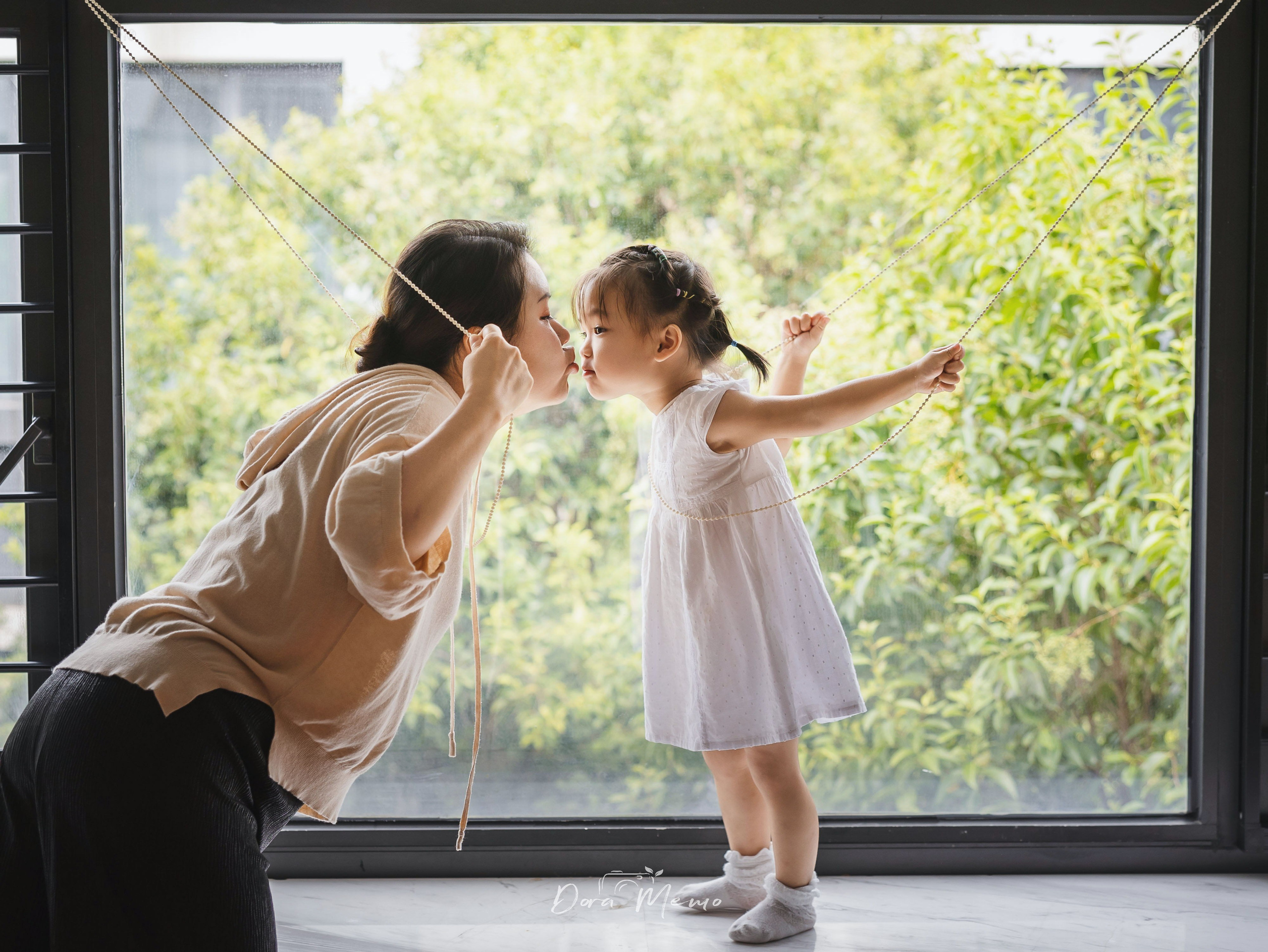 Mother kisses her daughter by the window in an emotional Shanghai family photography session.