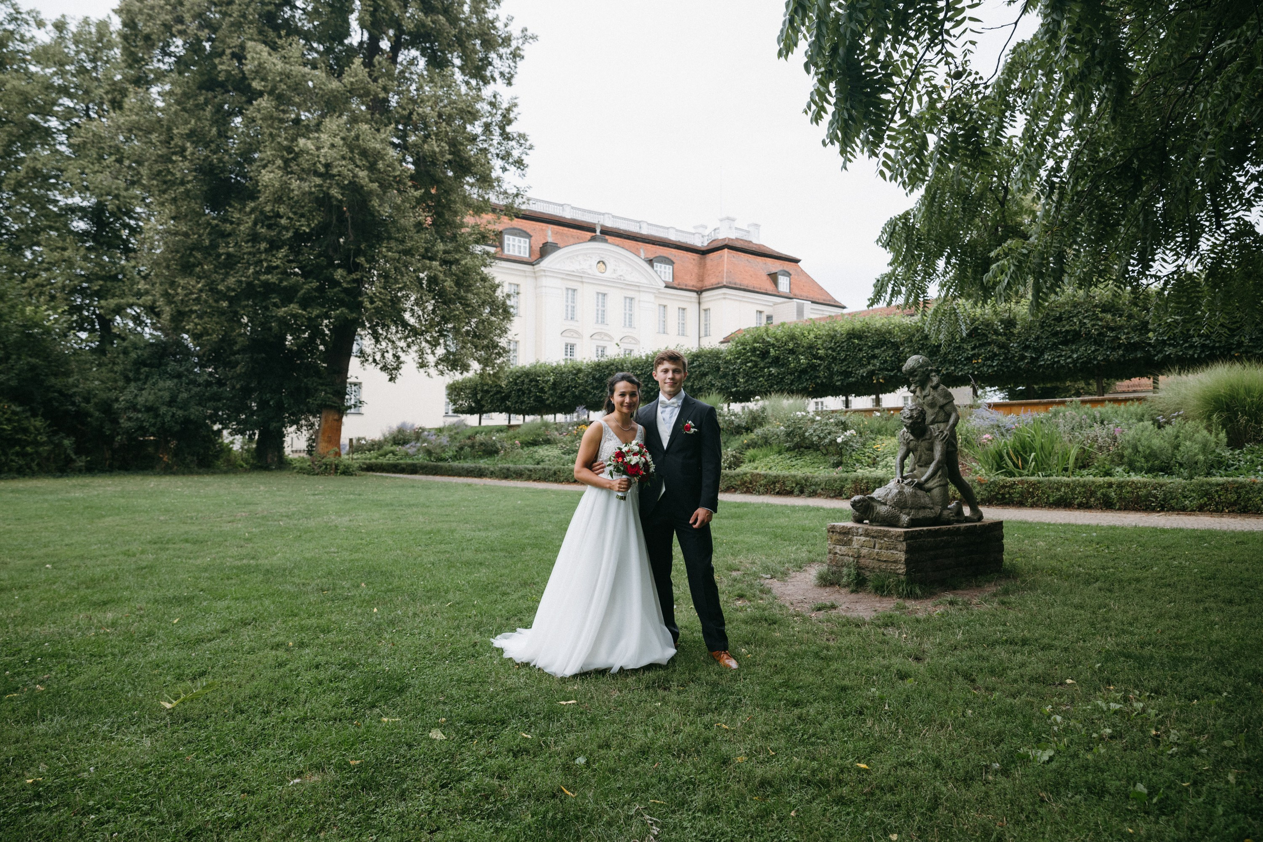 Brautpaar im Schlossgarten mit Statue im Hintergrund von Schloss Köpenick