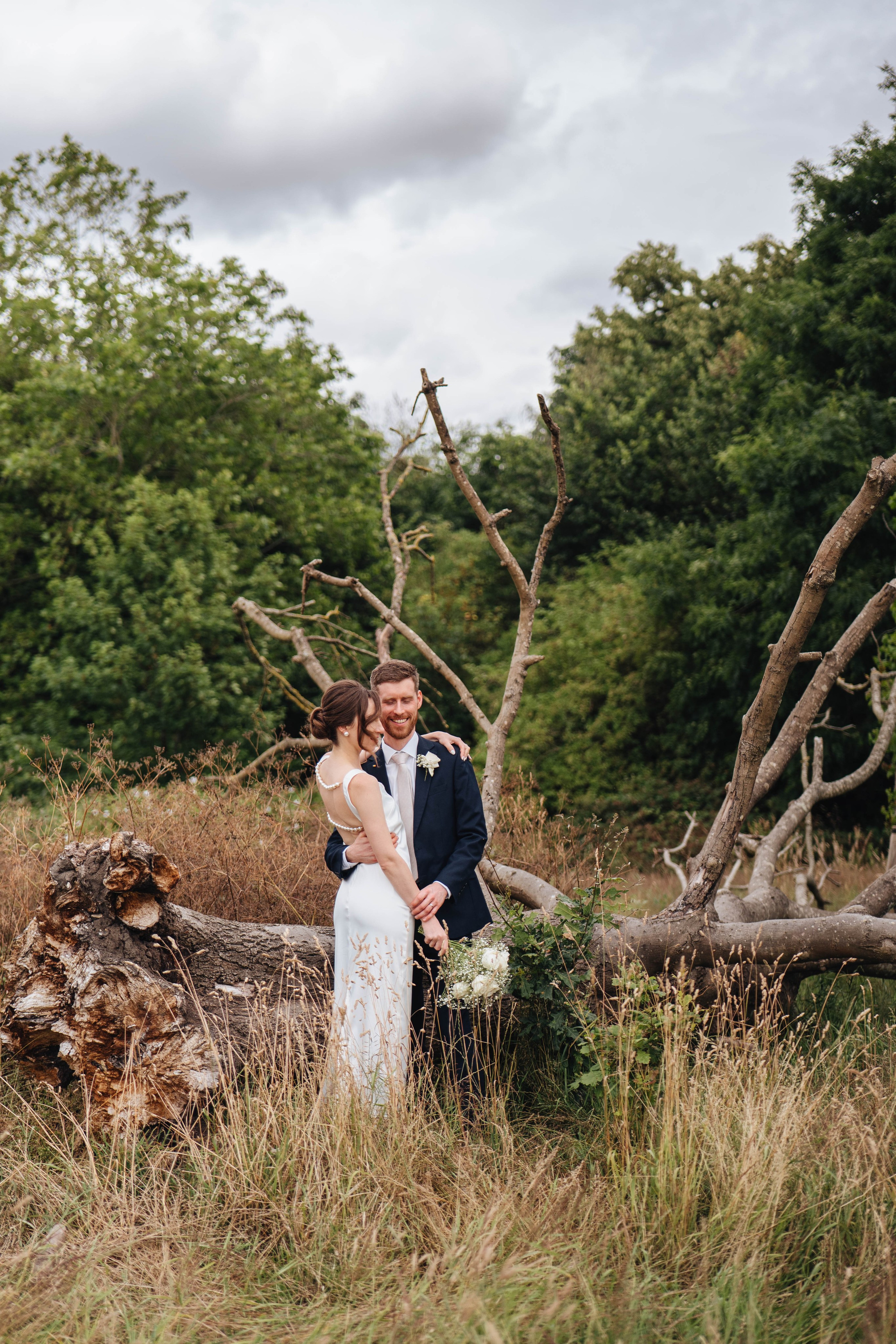 bride and groom posing near an old dead tree
