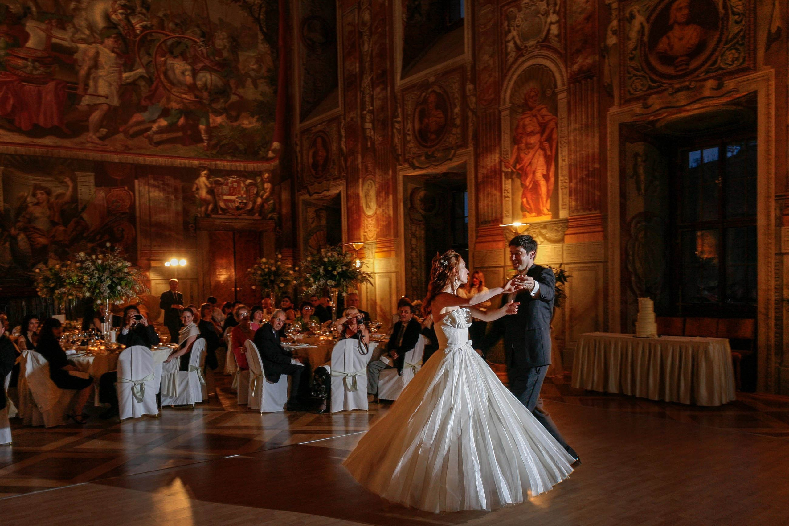 A bride is taken by the hand and spun around in the historic grand ballroom at the Troja Palace.