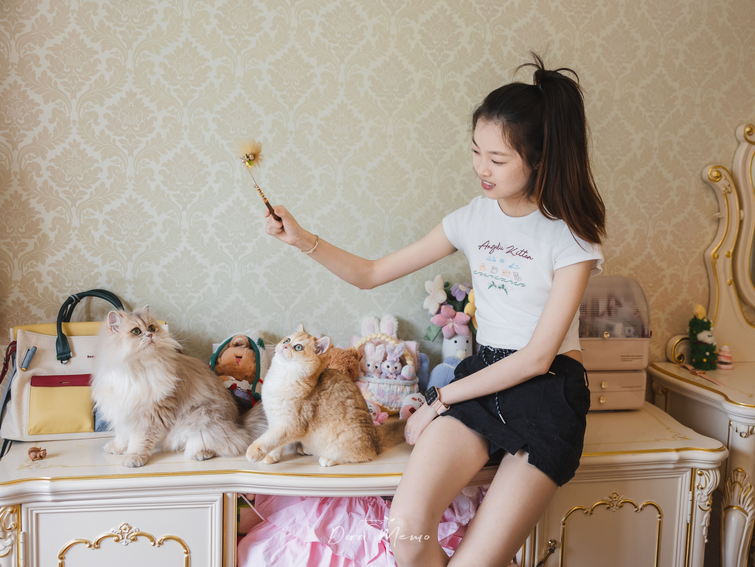 A woman plays with two cats at home in a natural Shanghai lifestyle photography session.