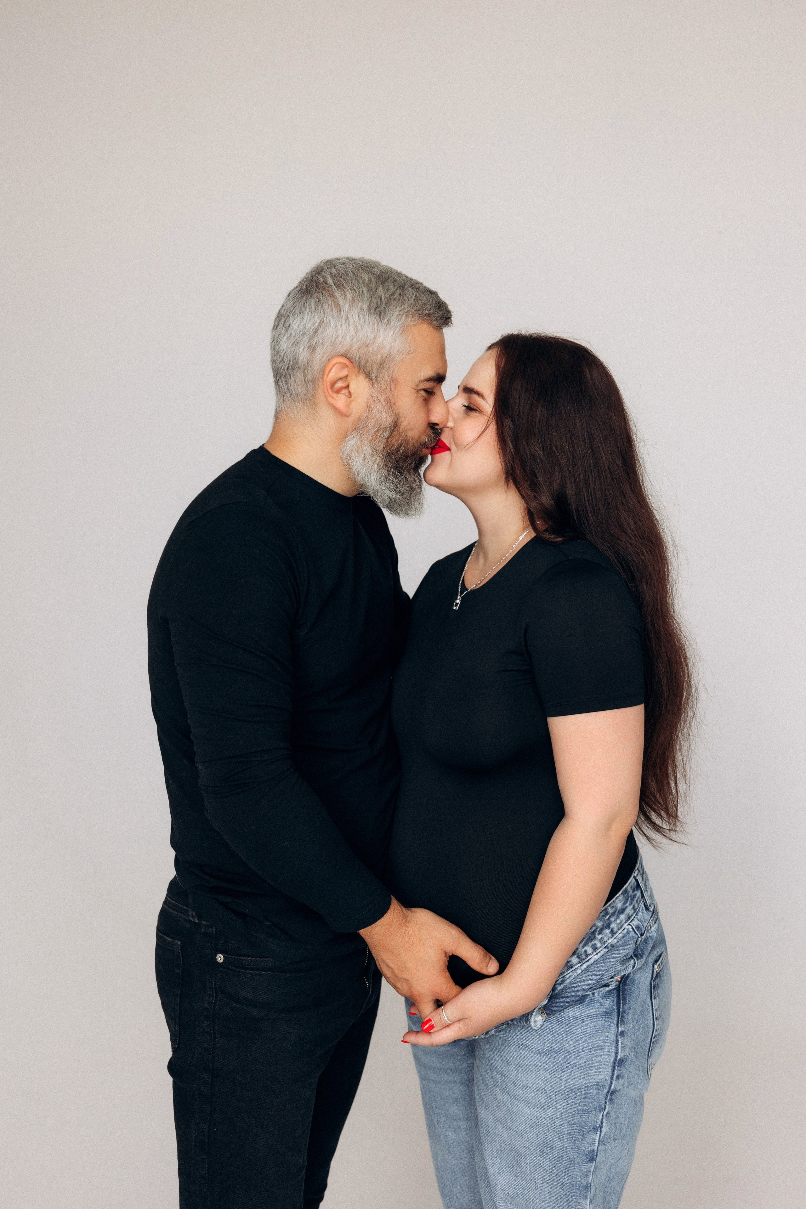 Sesja ciążowa dla par – mężczyzna obejmuje przyszłą mamę, subtelność i wsparcie w jednym ujęciu.