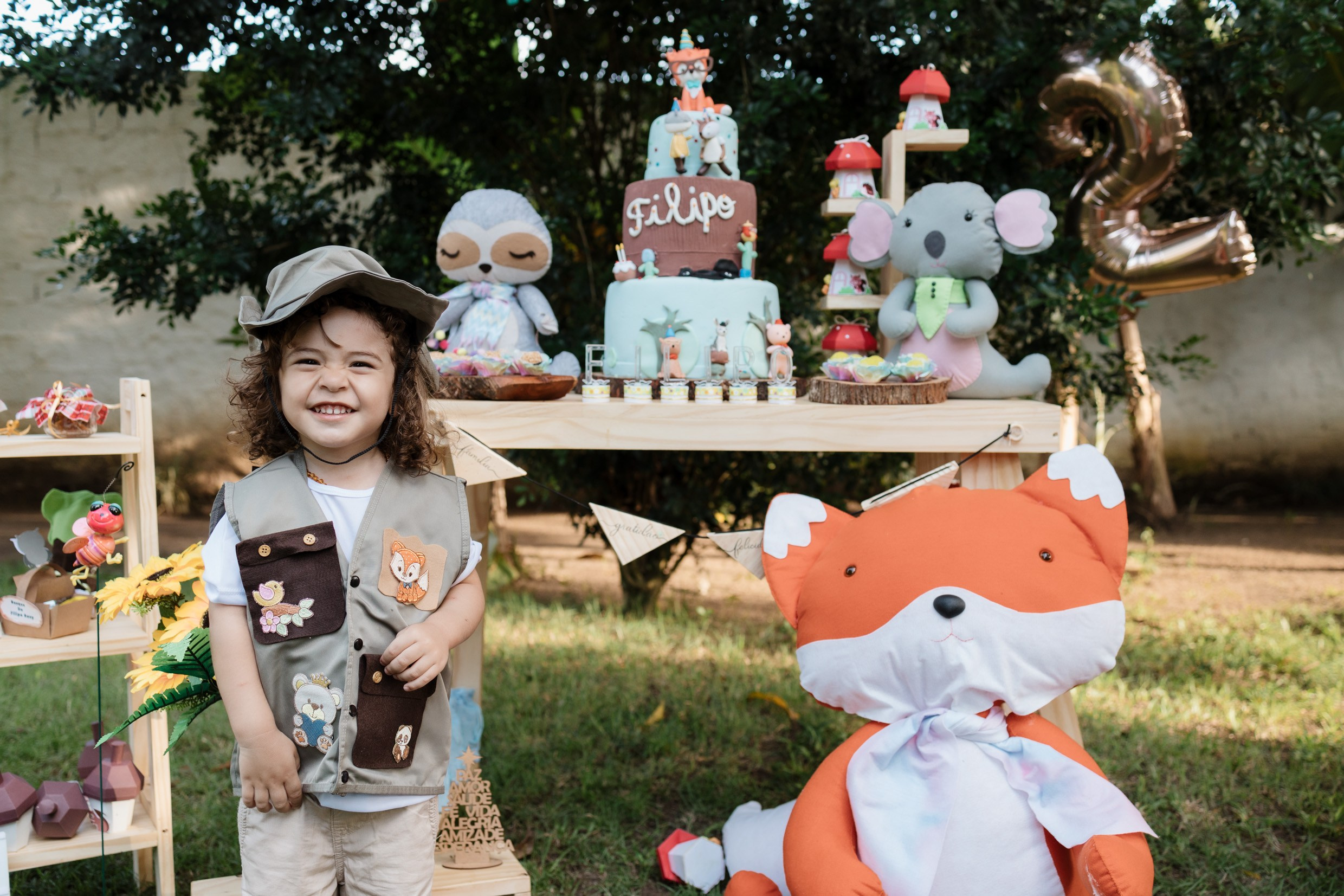 Menino sorrindo em frente a decoração de festa infantil externa