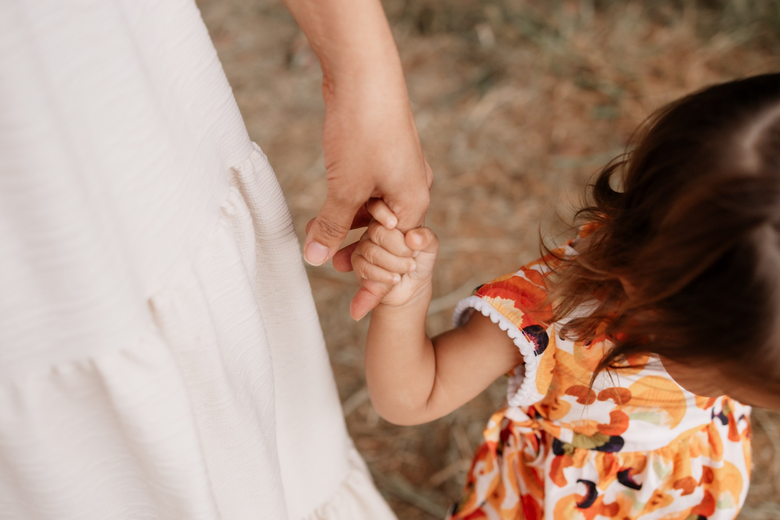 Mãe e filha caminhando de mãos dadas em ensaio de família