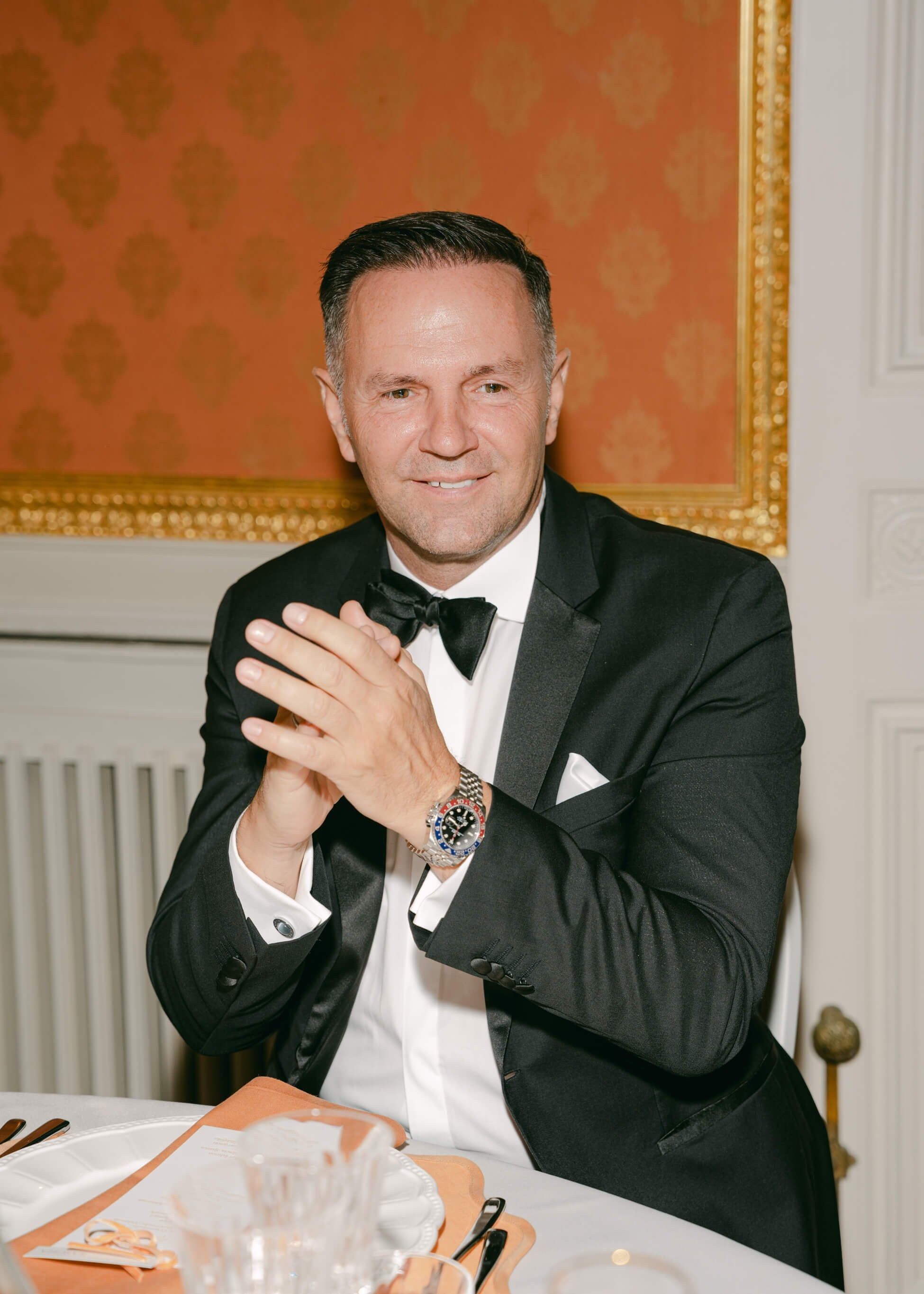 Wedding guest in tuxedo clapping enthusiastically at luxury reception dinner, Villa Rothschild Frankfurt