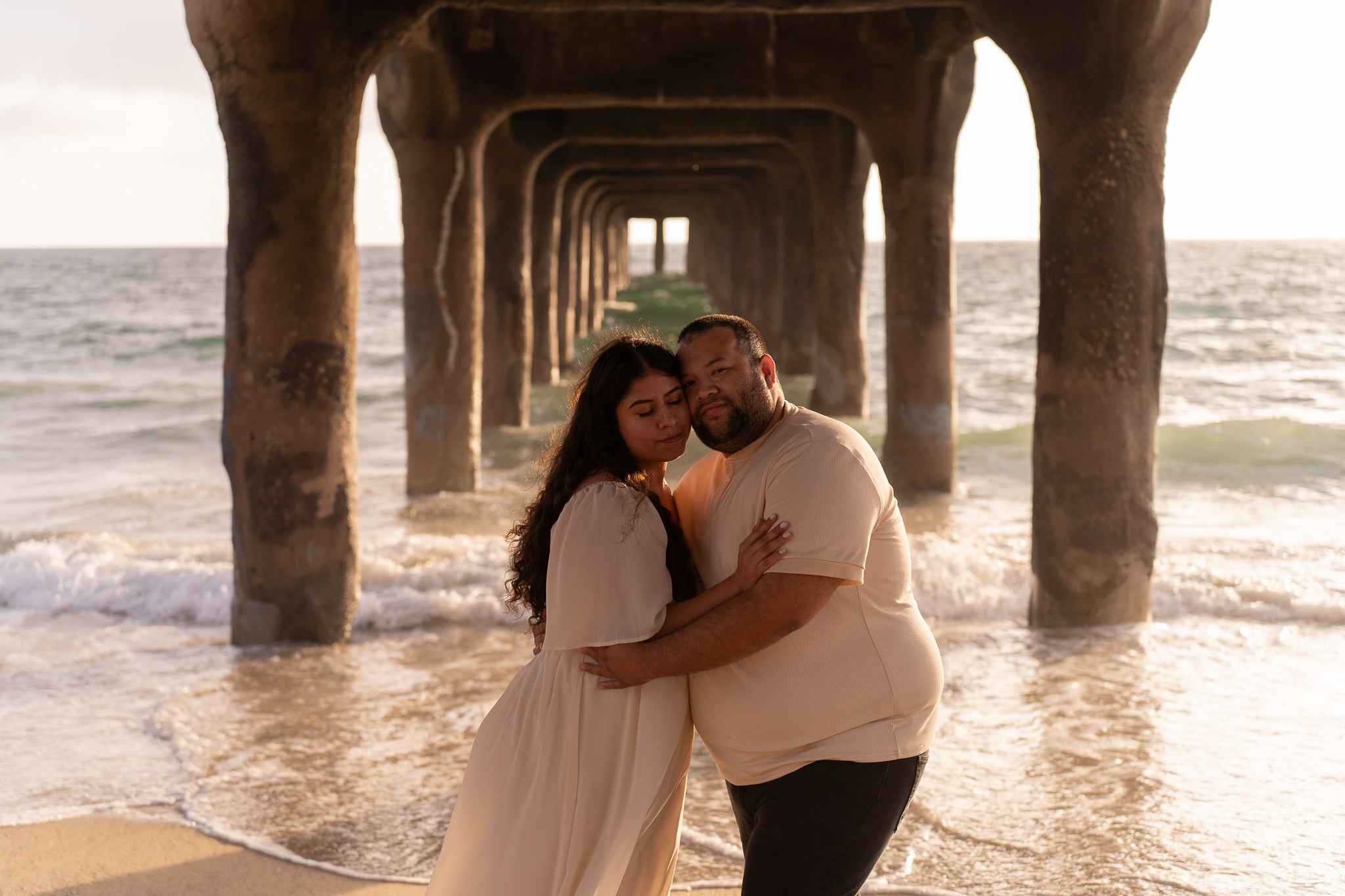 Romantic beach engagement photo of a couple holding hands near the ocean