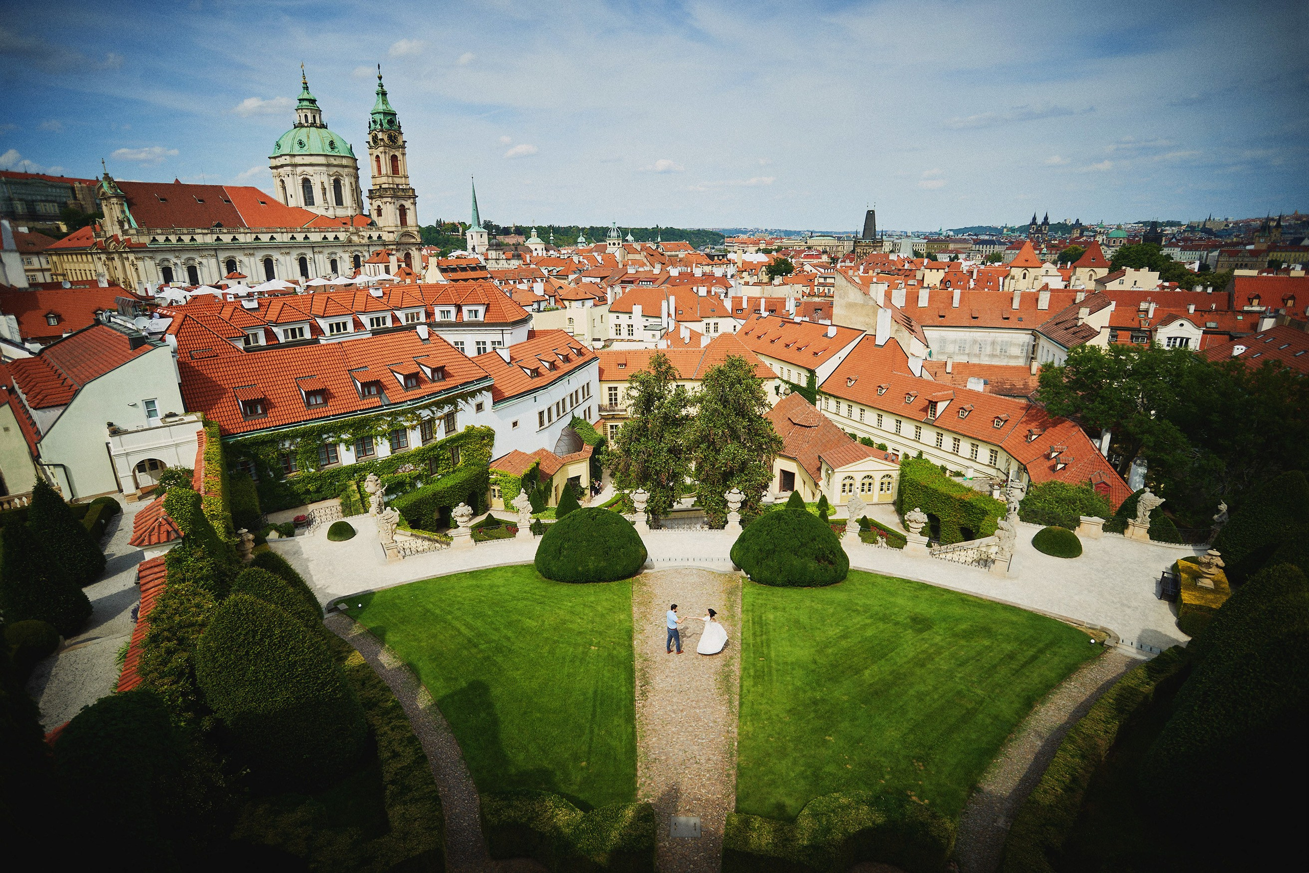 Bird's-eye view of couple walking hand-in-hand through the terraced landscape of Vrtba Garden, Prague.