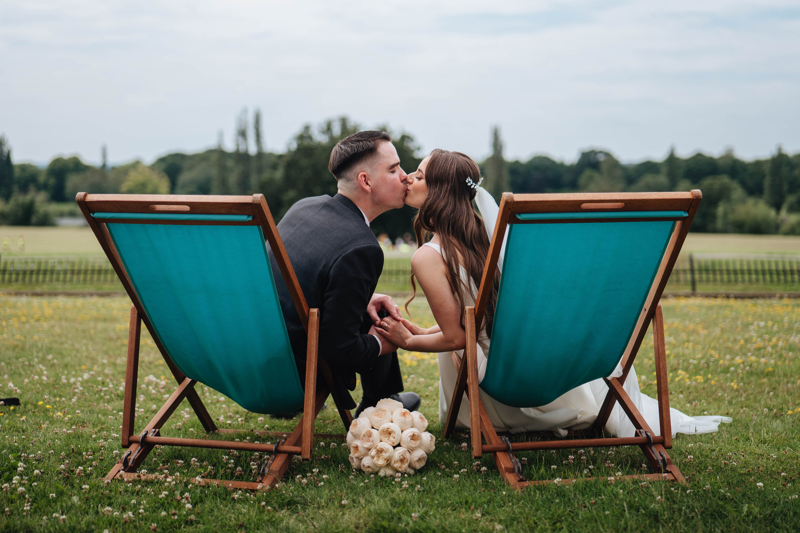 bride and groom sitting in chairs in the park and kissing, photo from the back