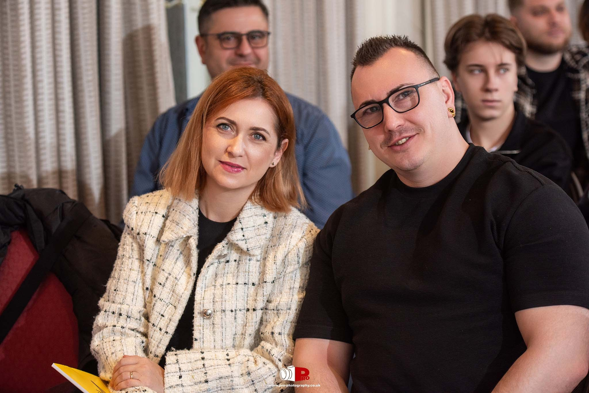 A man and woman smiling during a networking event, sitting in a relaxed environment.