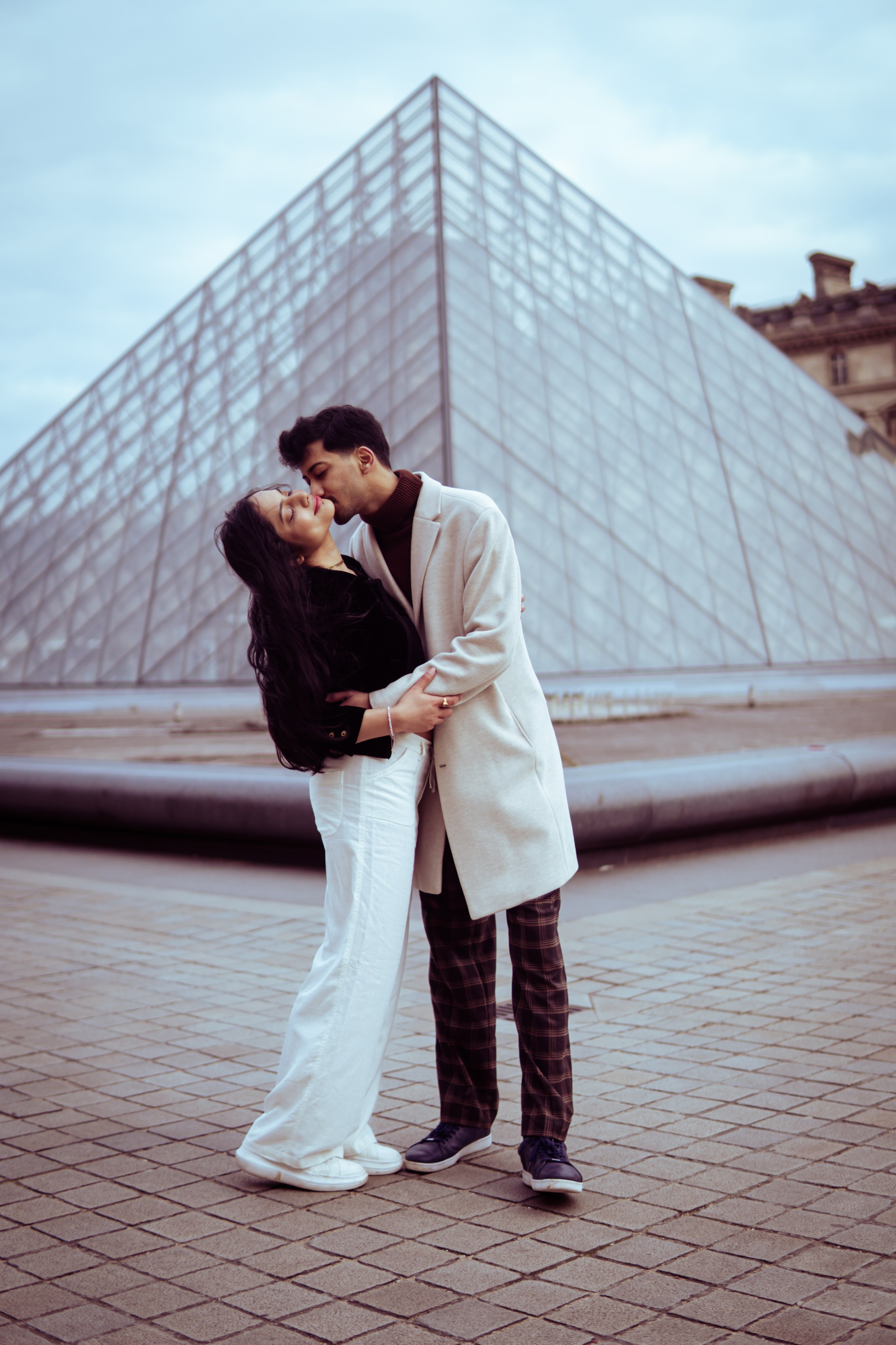couple standing in front of louvre museum