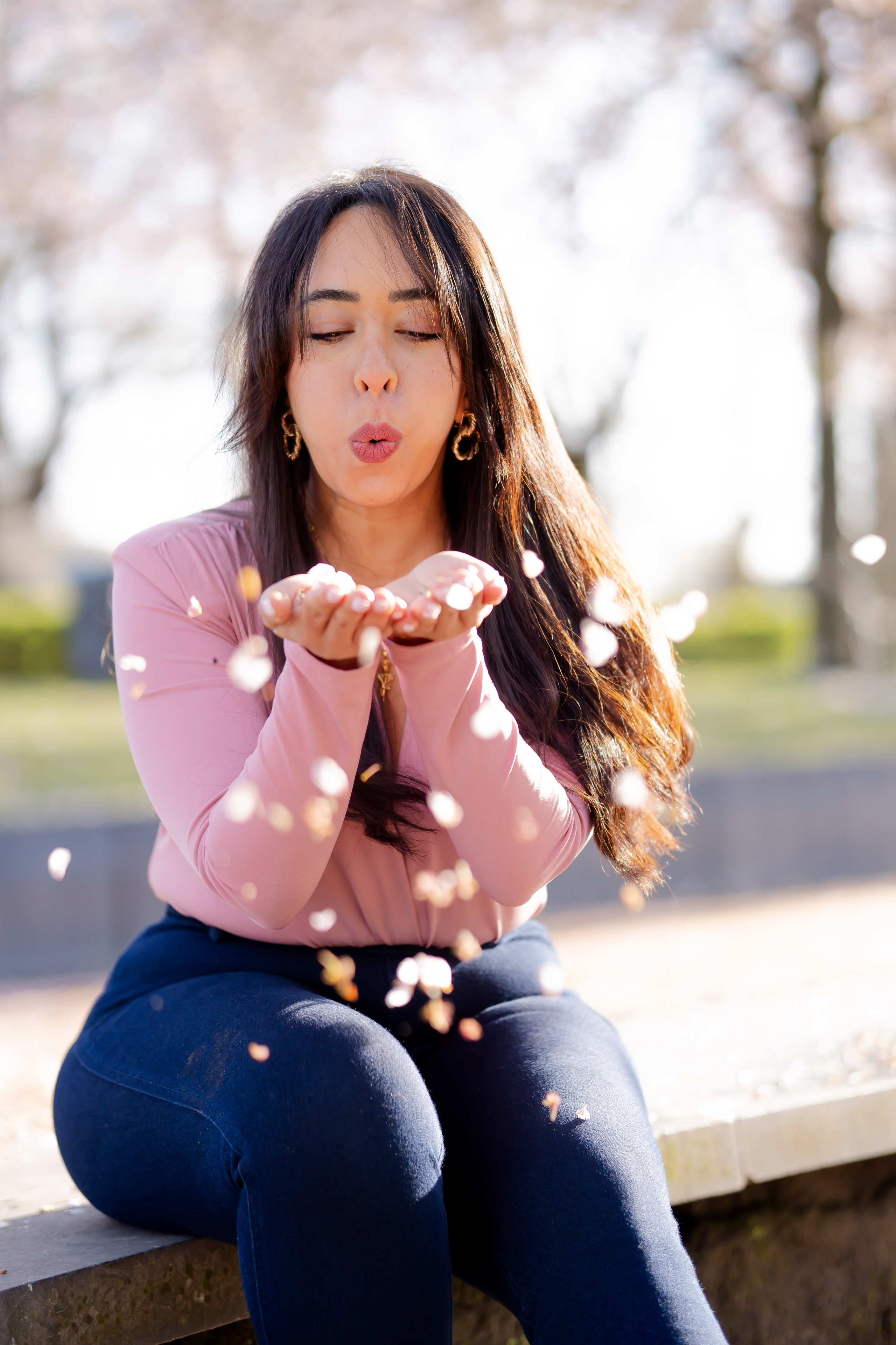 girl blowing the cherry blossoms on her palm