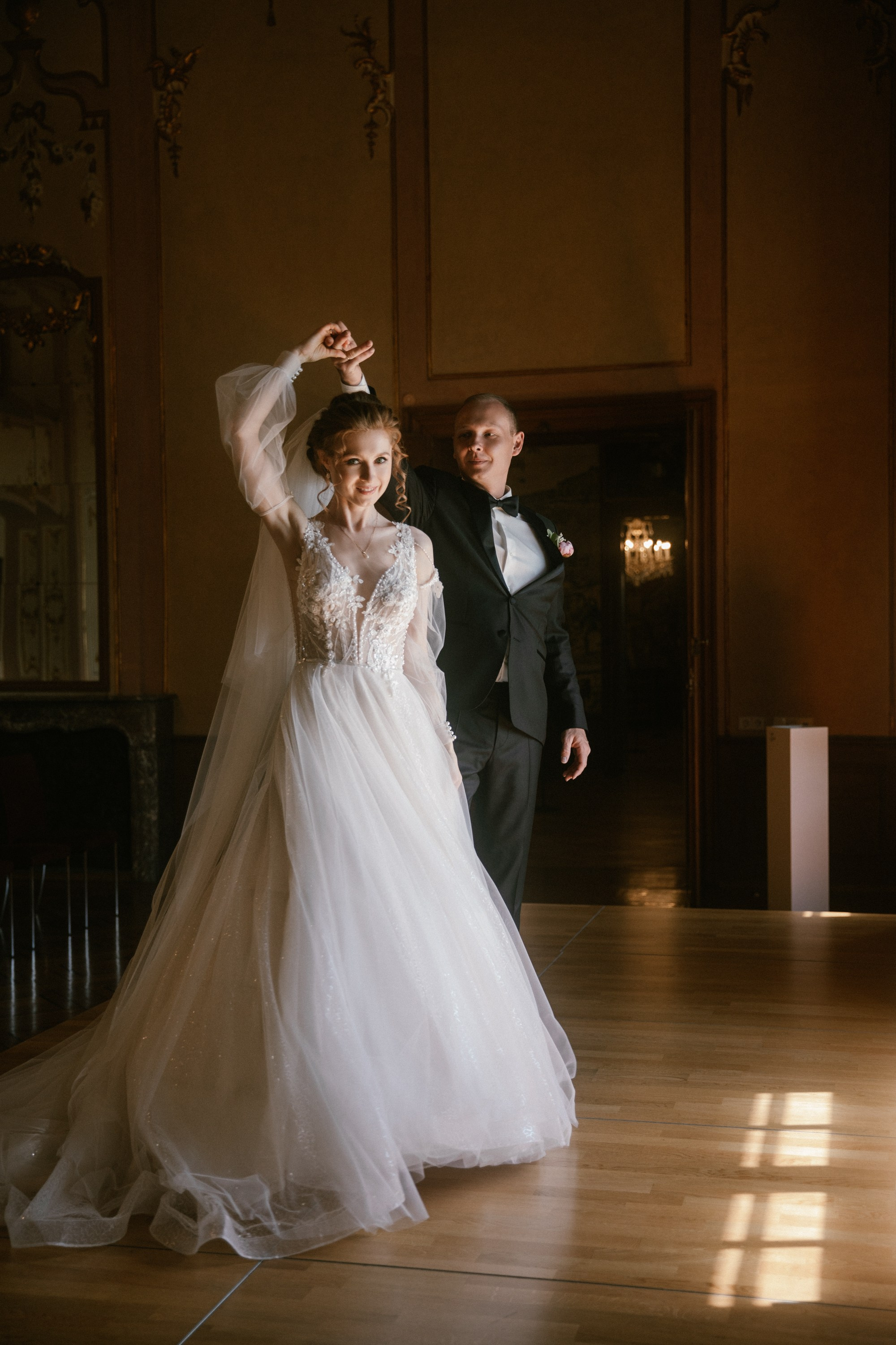 Braut tanzt mit erhobenem Arm mit Bräutigam im Spiegelsaal