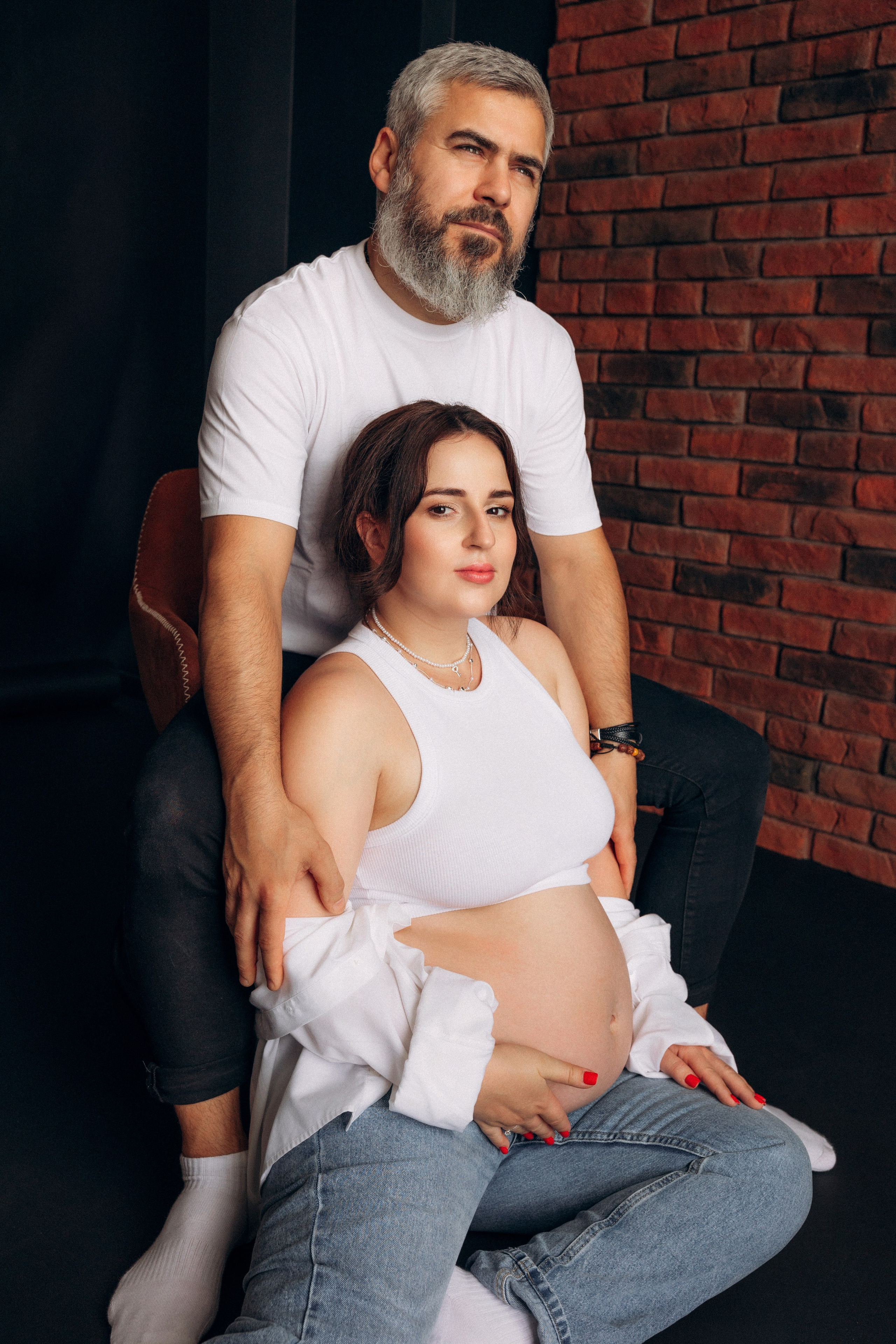 Radość w duecie – spontaniczny moment śmiechu w ciążowej sesji pary, jasna przestrzeń i naturalne emocje.