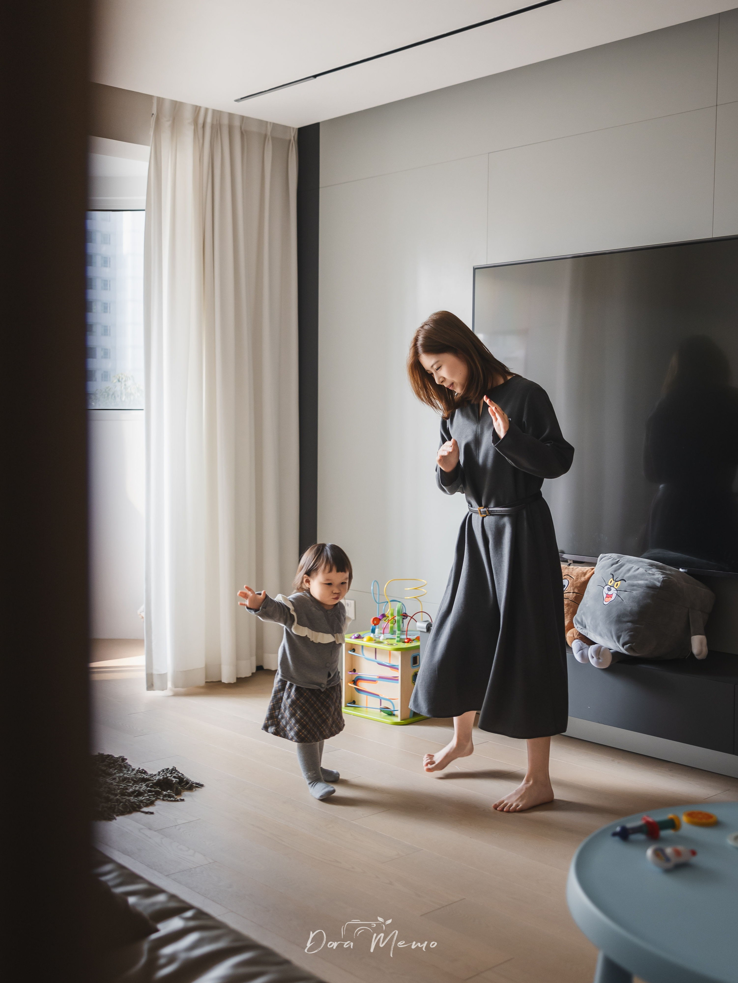 A mother and her two-year-old daughter playing by the window in their Shanghai home, captured by a family photographer during a natural lifestyle session.