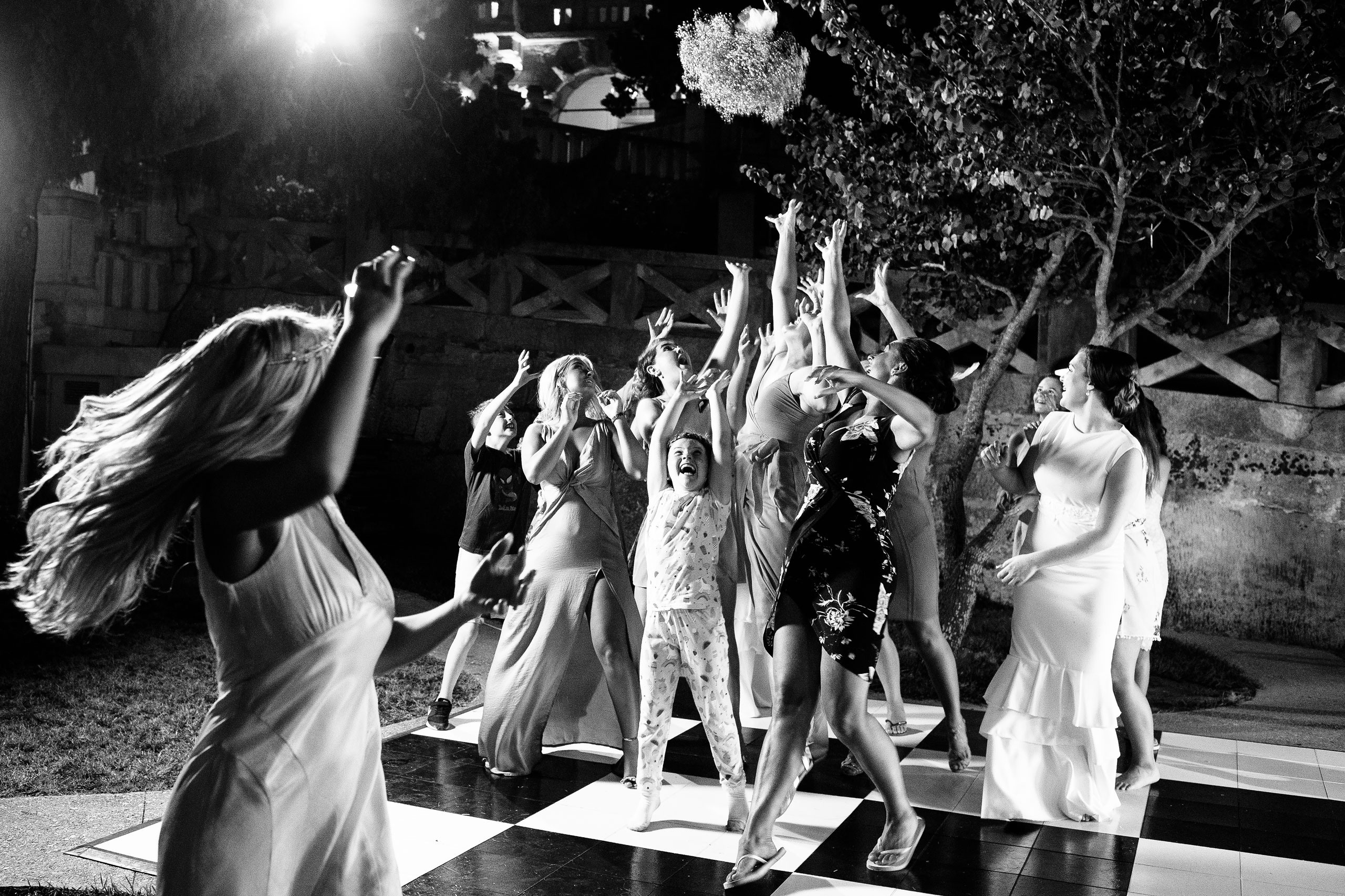 bride is tossing the bucket at her wedding and guests are trying to catch it