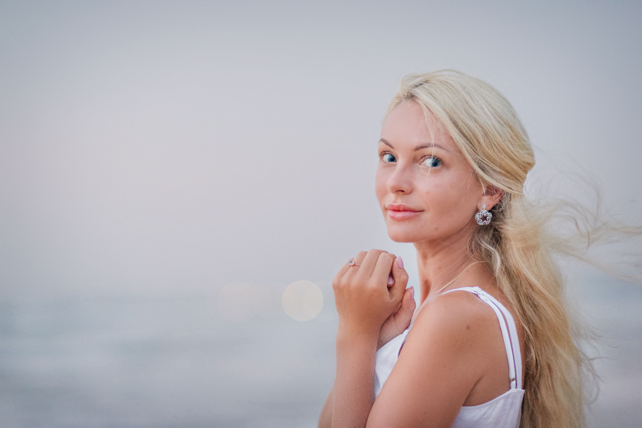 beautiful blonde lady with long hair and blue eyes near an ocean 