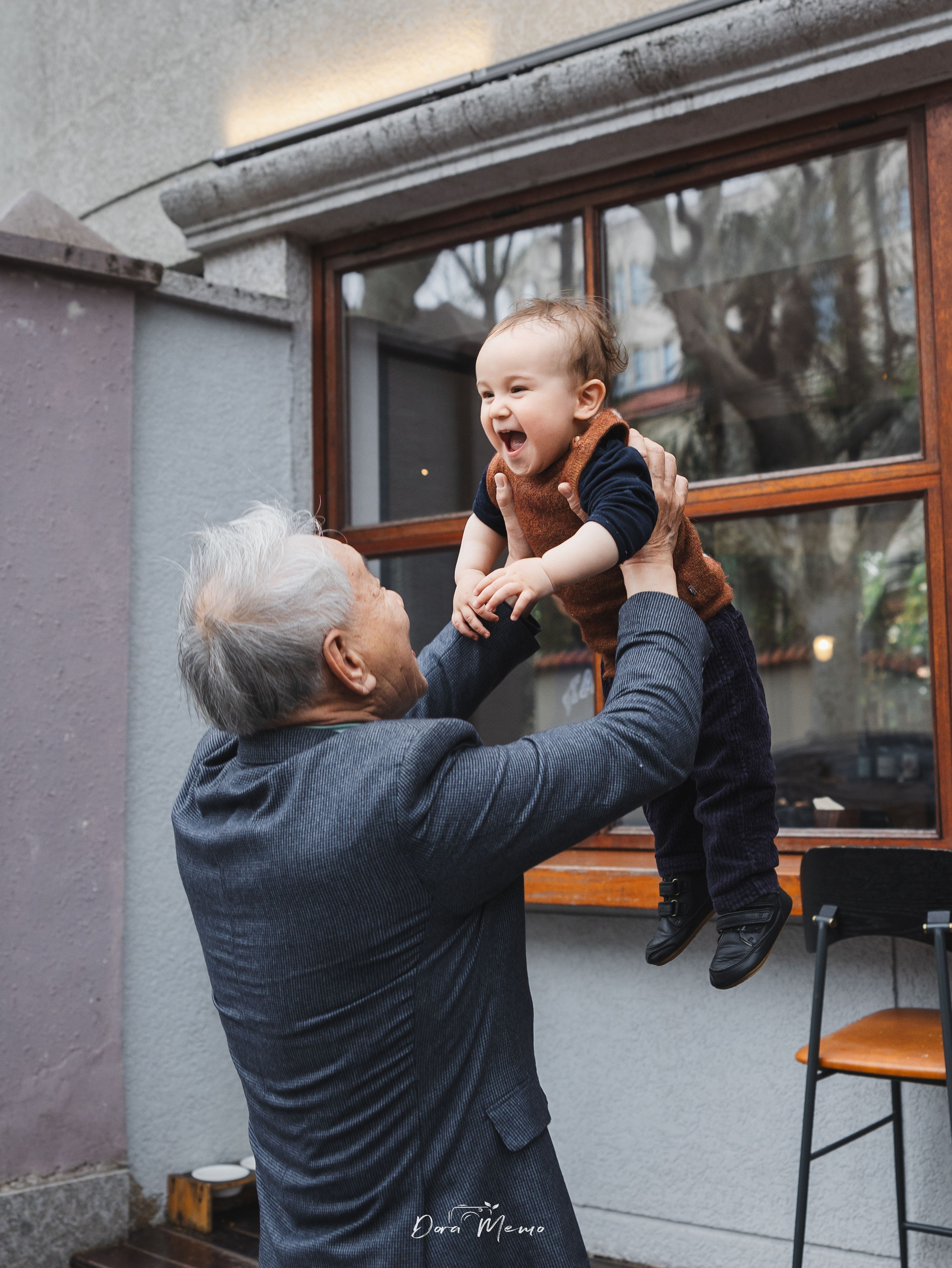 In this family photo, grandpa is playing "lift high" with the baby.