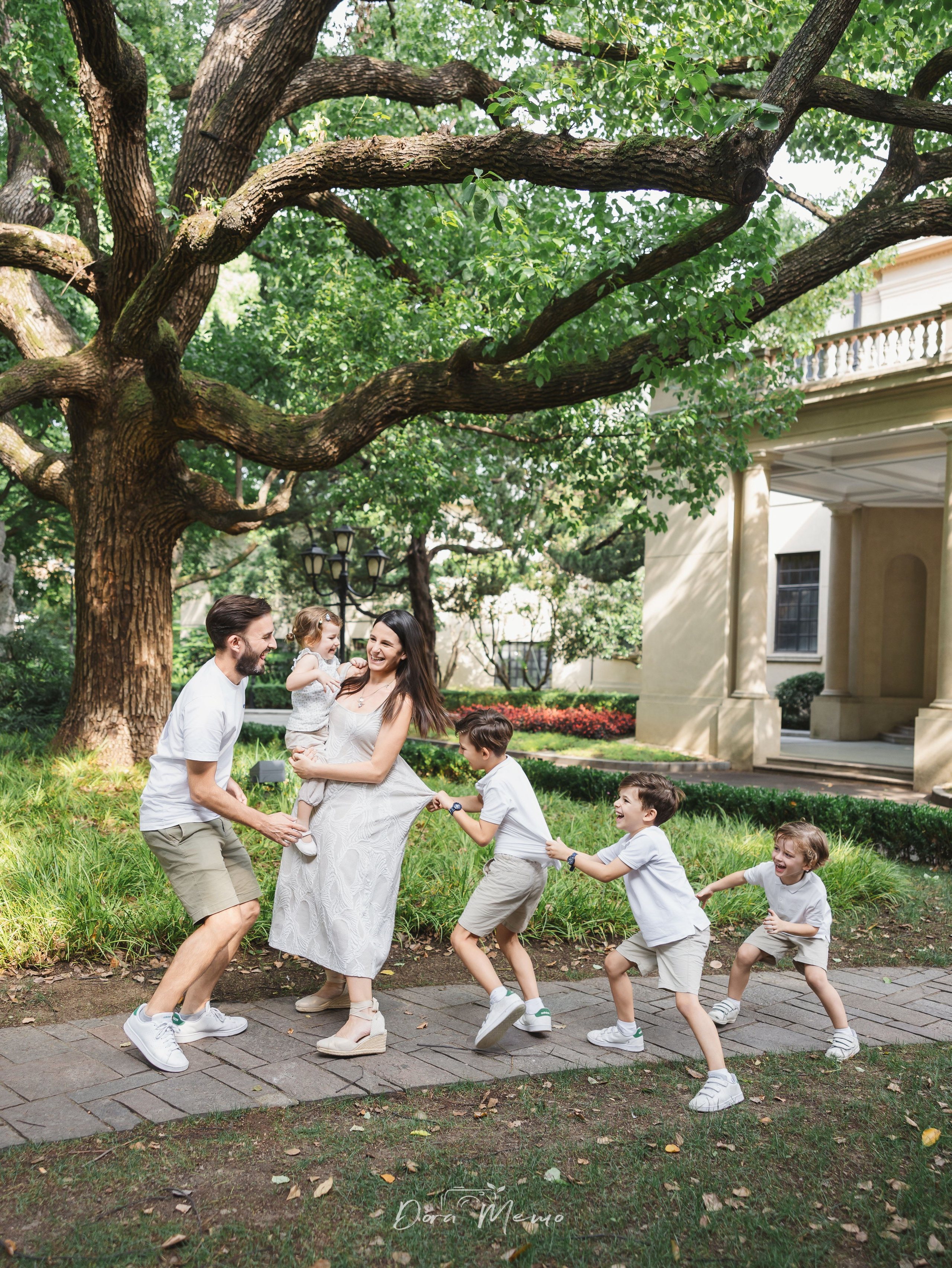 Whole family in garden, kids clustering around mom | A family of six enjoying a summer afternoon in a Shanghai garden, kids laughing and playing together 