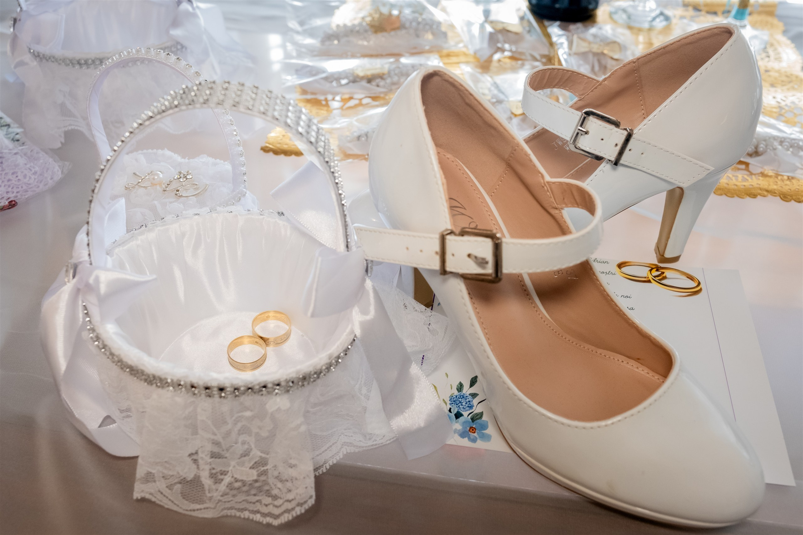 Alianzas de boda en una cesta junto a los zapatos blancos de la novia